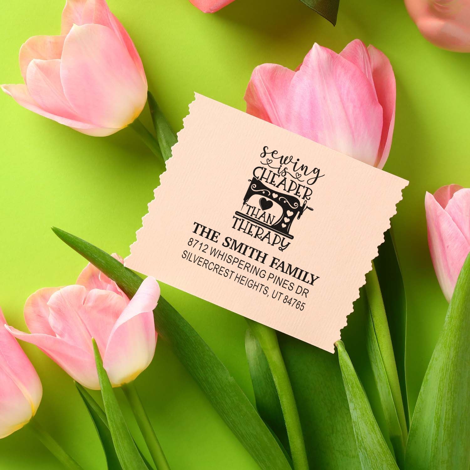 Personalized address stamp with sewing is cheaper than therapy design, displayed among pink tulips on a bright green background.