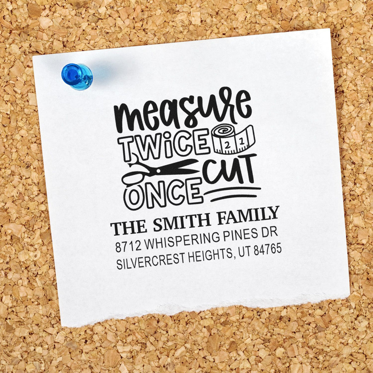 Custom address stamp on white paper pinned to corkboard, featuring measure twice cut once with scissors and tape measure for The Smith Family.