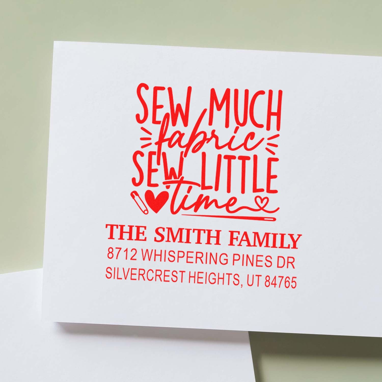 Personalized red rubber stamp on white card reading Sew Much Fabric, Sew Little Time with The Smith Family address.