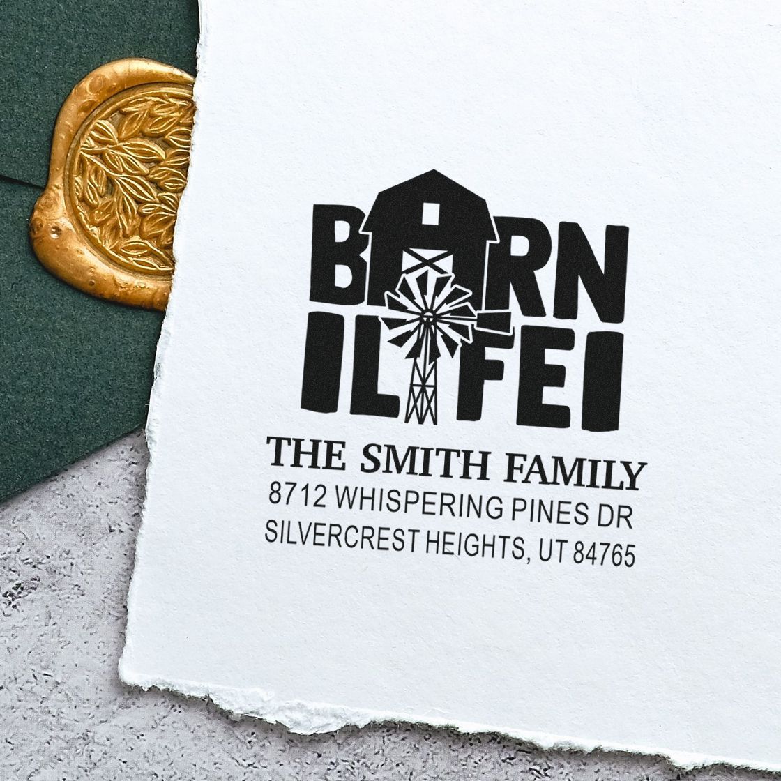 Custom address stamp with barn logo for The Smith Family on torn white paper, beside a gold wax seal on a dark green surface.