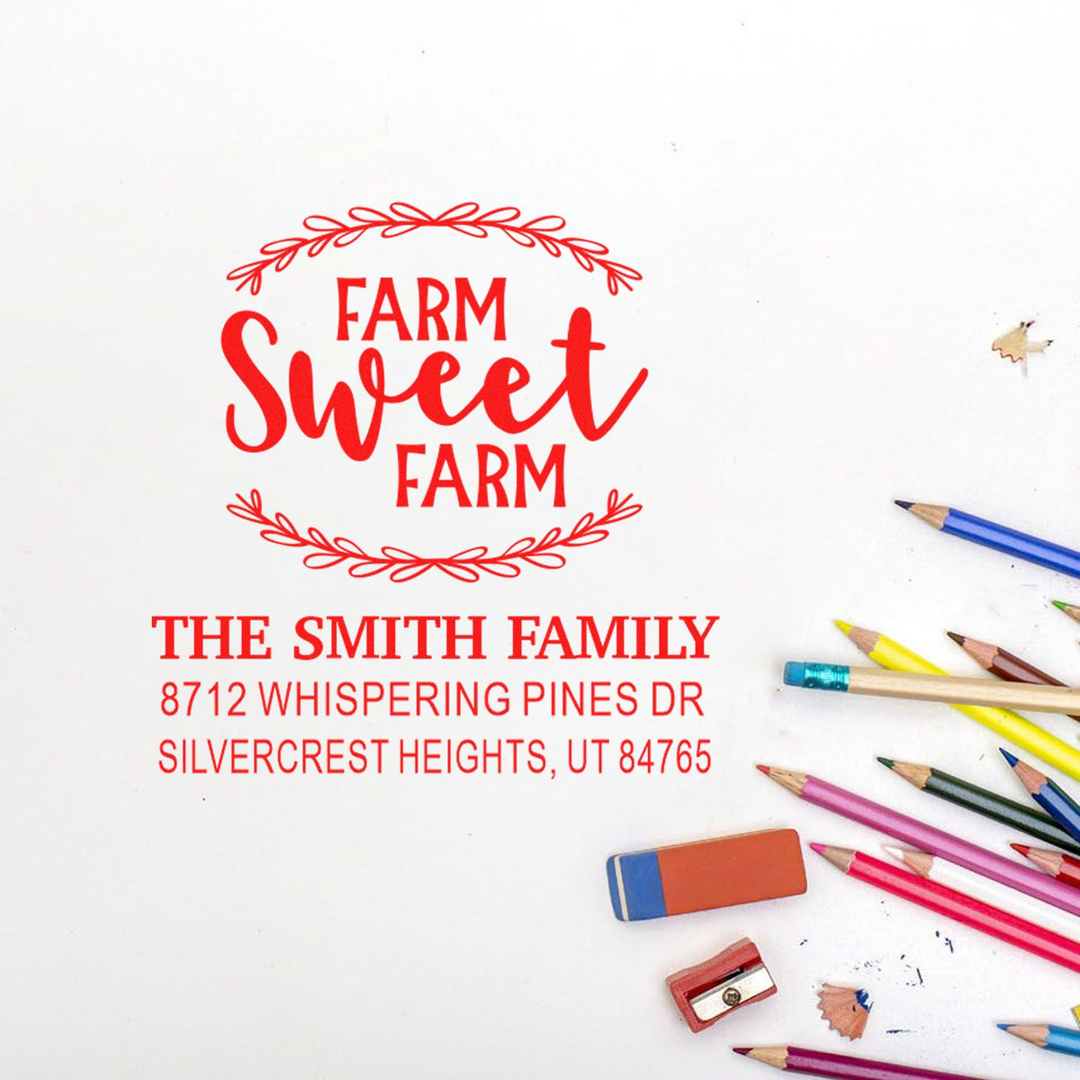 Custom red Farm Sweet Farm address stamp for The Smith Family on white paper, with colored pencils and erasers nearby.