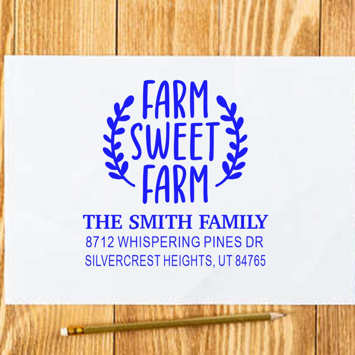 Custom Farm Sweet Farm address stamp with family name and address on white paper, set on a wooden table with pencil.