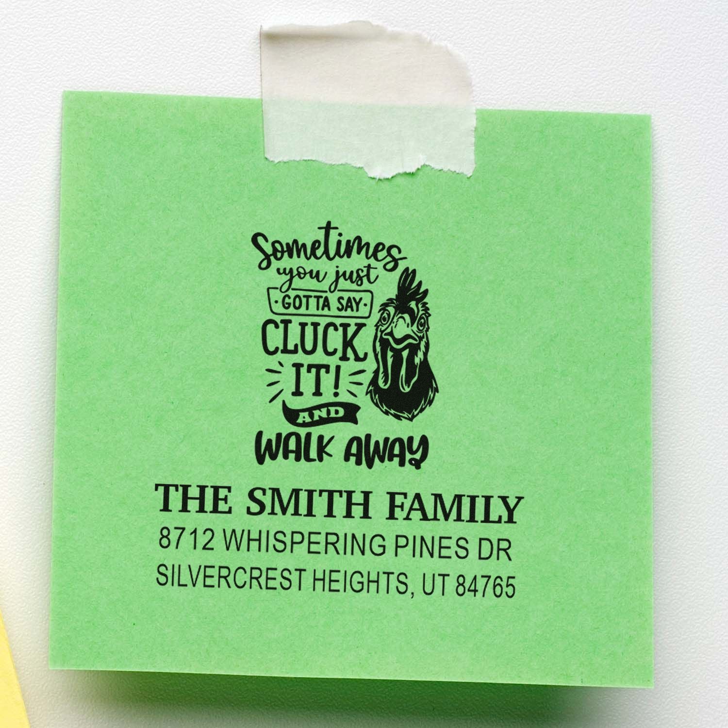 Custom green address stamp with humorous chicken design and Smith family address, taped to a white background.