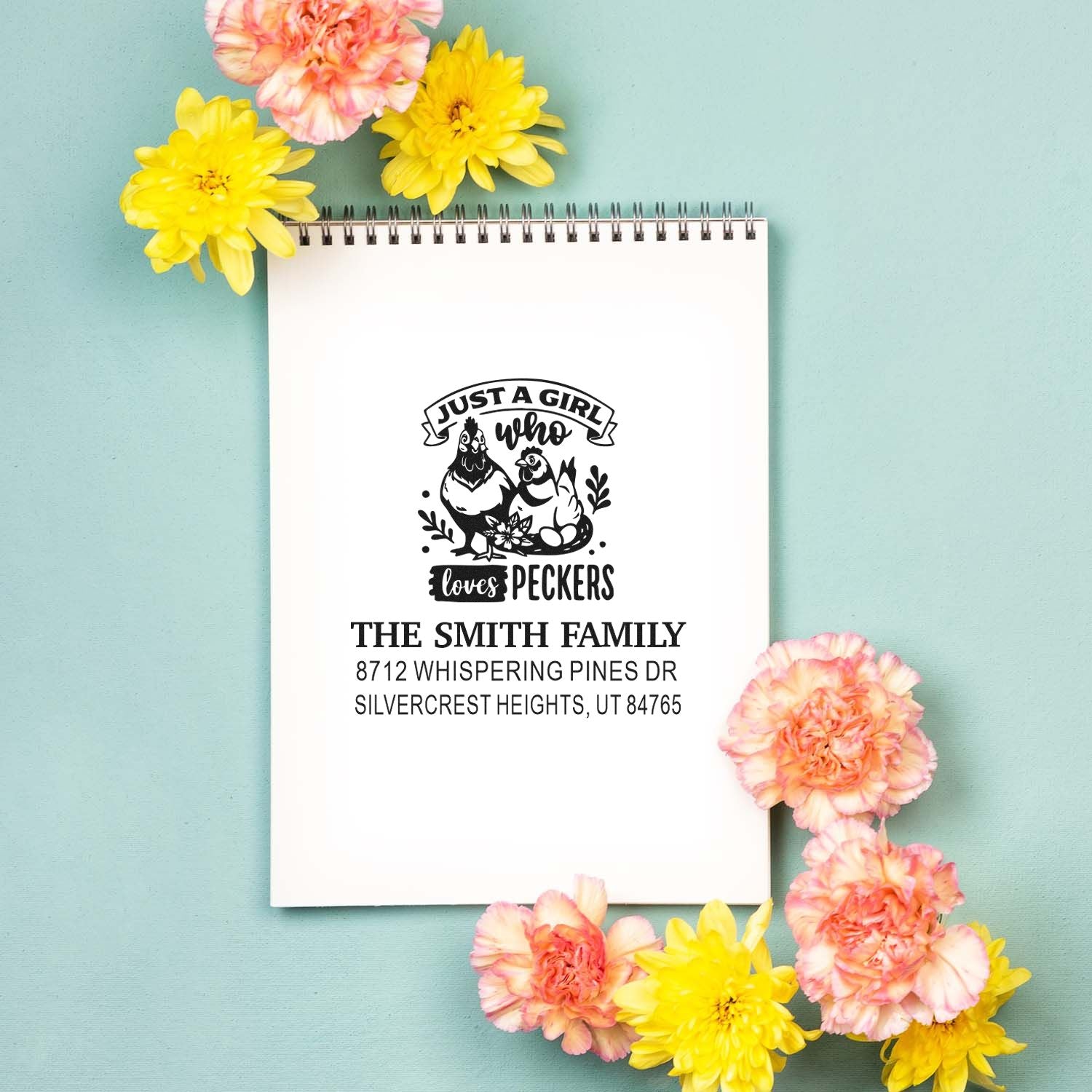 Personalized chicken address stamp on spiral notepad, surrounded by yellow and pink flowers on a teal background.