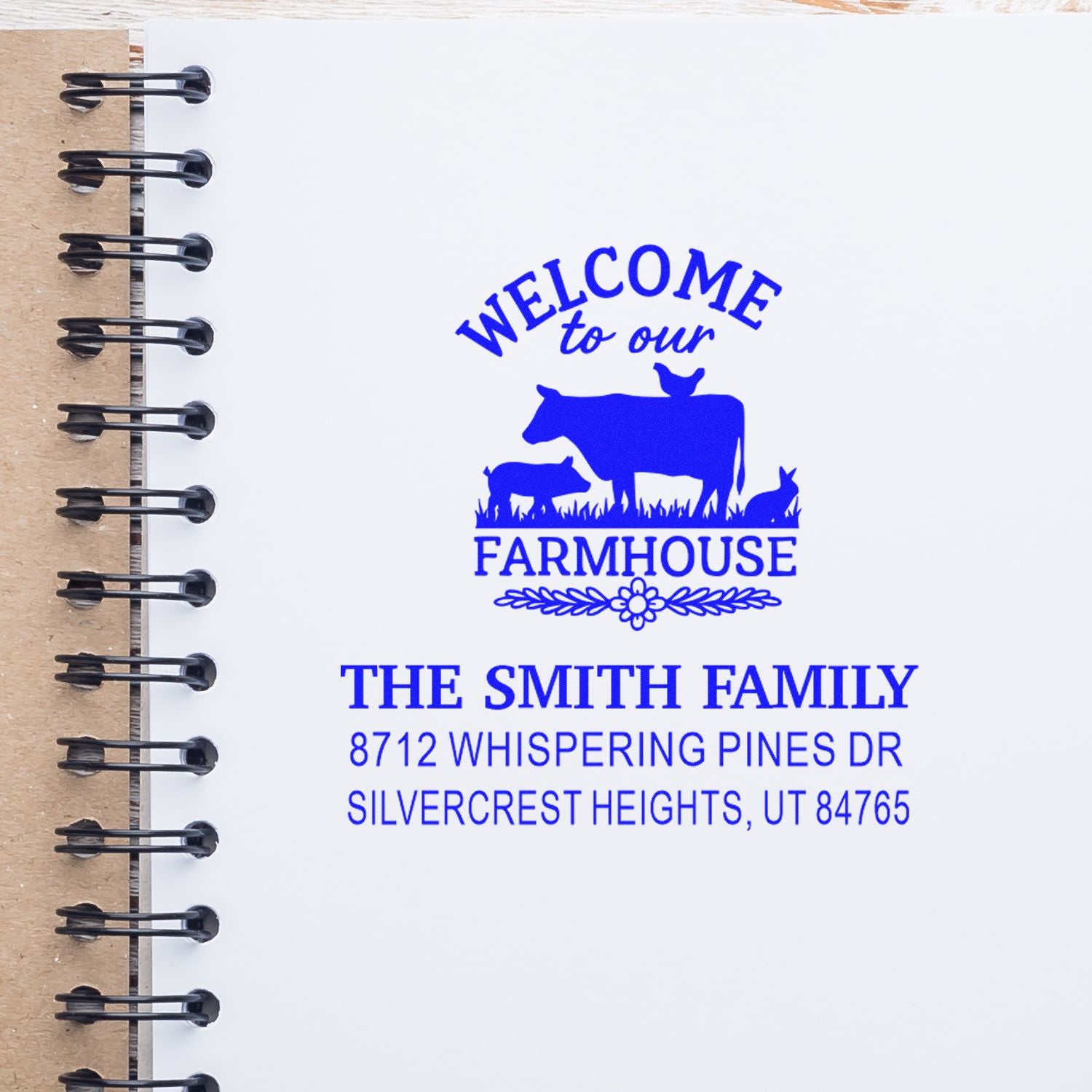 Blue custom farmhouse return address stamp on spiral notebook page, featuring cow, pig and rabbit with The Smith Family Utah address.