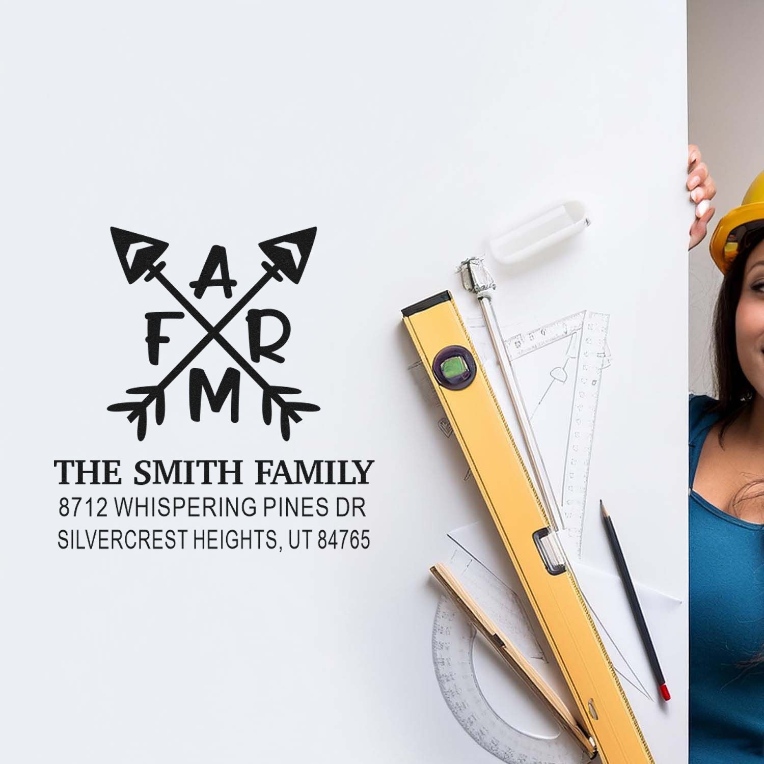 Custom family address stamp with monogram logo on white board, surrounded by drafting tools and a woman holding the display.