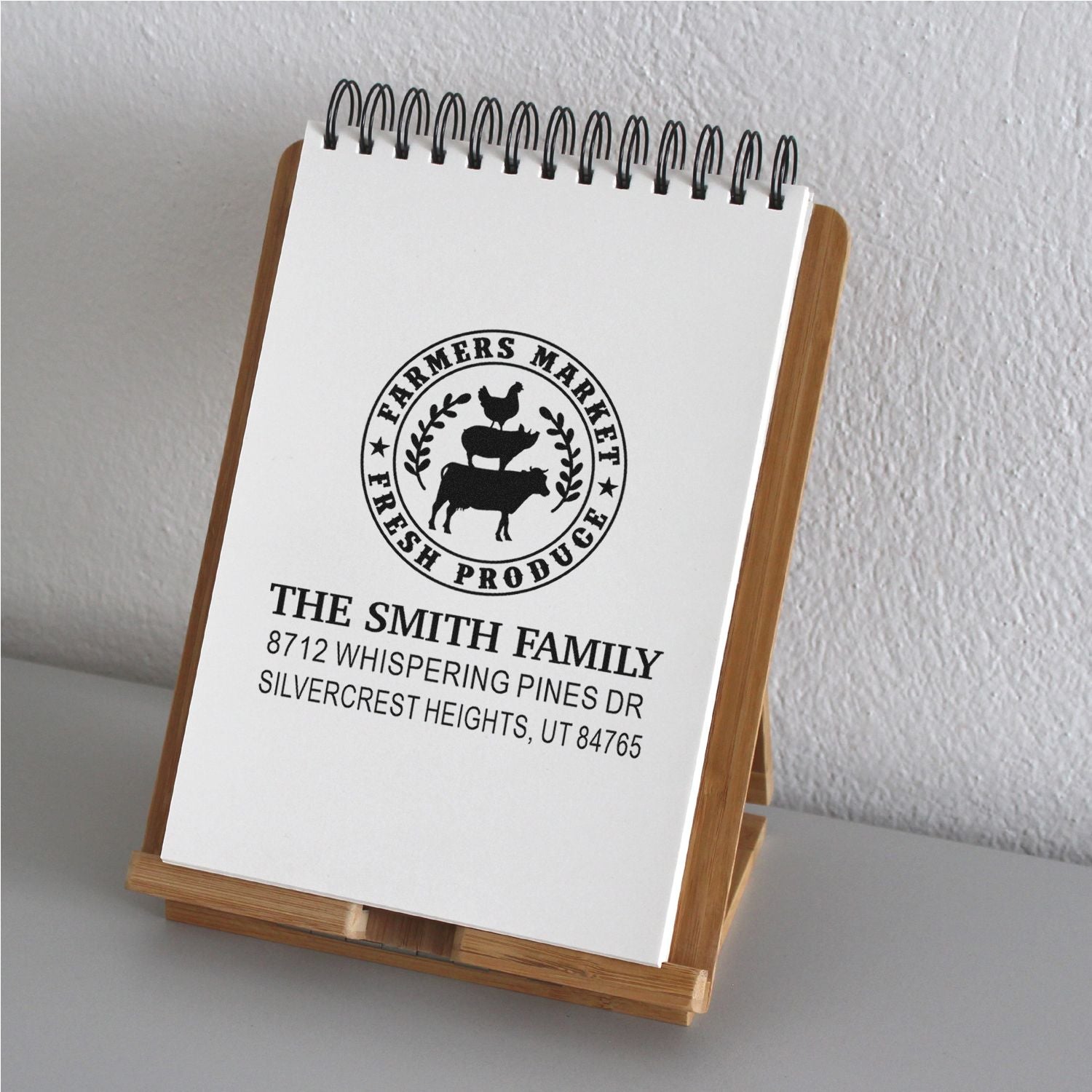 Custom farmers market fresh produce rubber stamp on a notepad stand, showing the Smith family name, farm logo, and address.