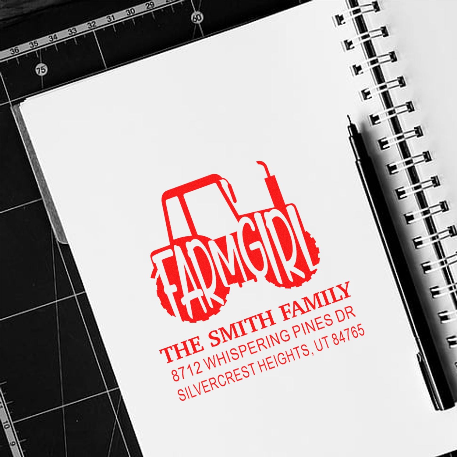 Personalized red farm tractor address stamp on a spiral notebook, featuring the Smith family name and Utah address.