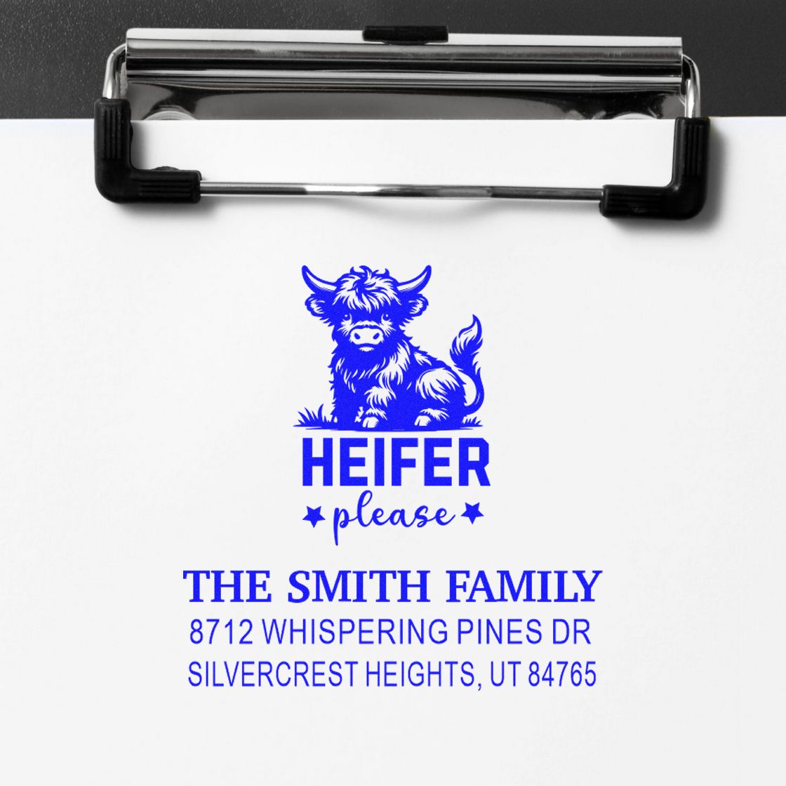 Custom blue address stamp on paper clipboard featuring a cow and Heifer Please, with The Smith Family address in Silvercrest Heights, UT.