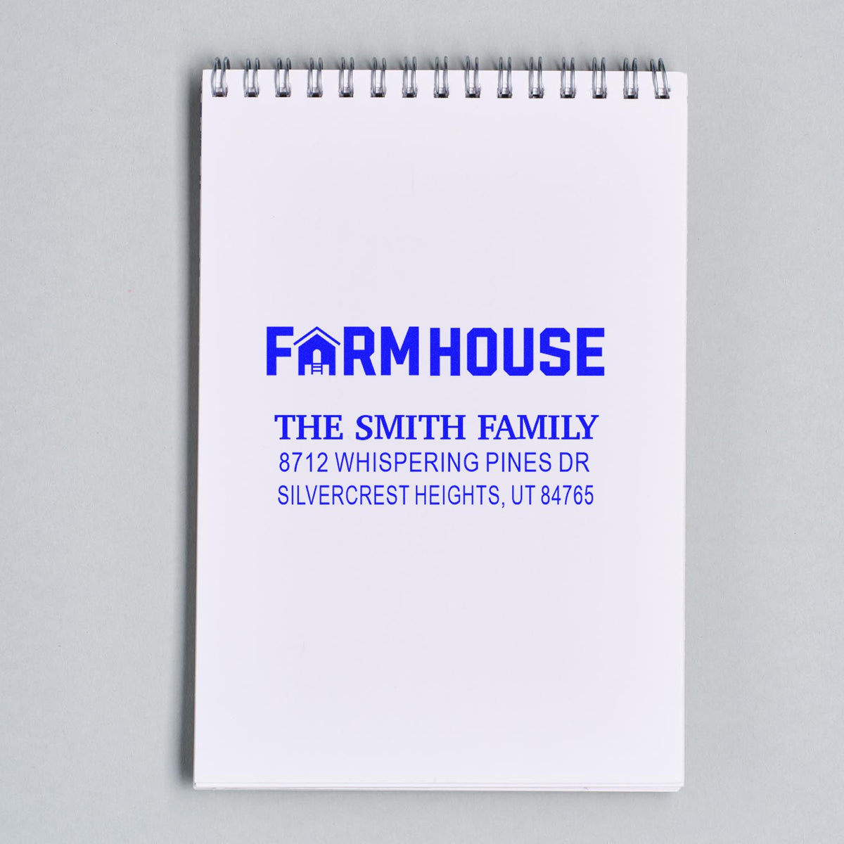 Custom farmhouse family return address stamp on a white spiral notepad, featuring a blue house icon, Smith family name, and address.