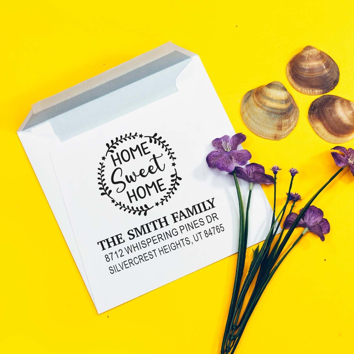 Custom return address stamp on white envelope with Home Sweet Home design, purple flowers, and seashells on a bright yellow background.