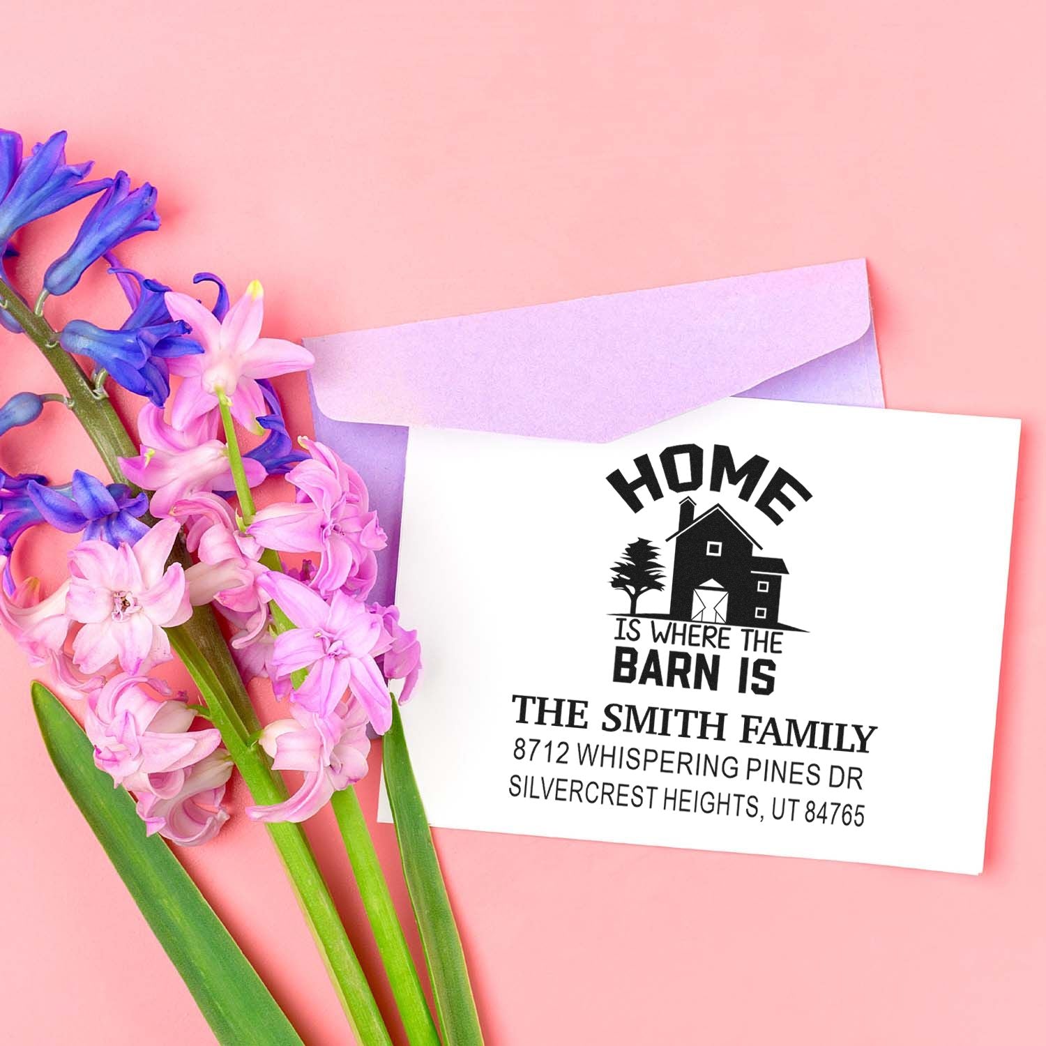 Custom farmhouse return address stamp on white card with lavender envelope and pink-purple hyacinths on a pastel pink background.