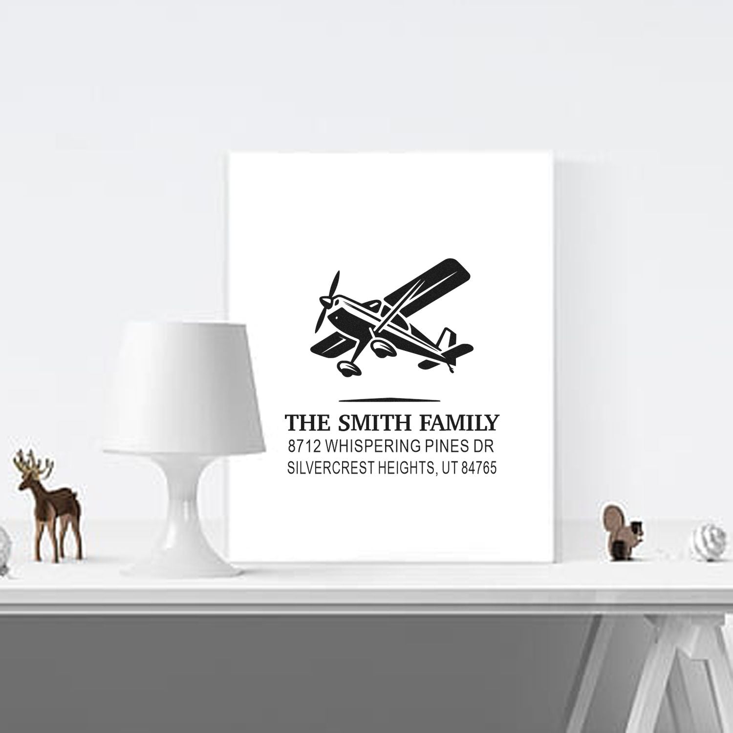 Personalized airplane return address stamp for The Smith Family, shown on a white card in a minimalist room with lamp and decor.