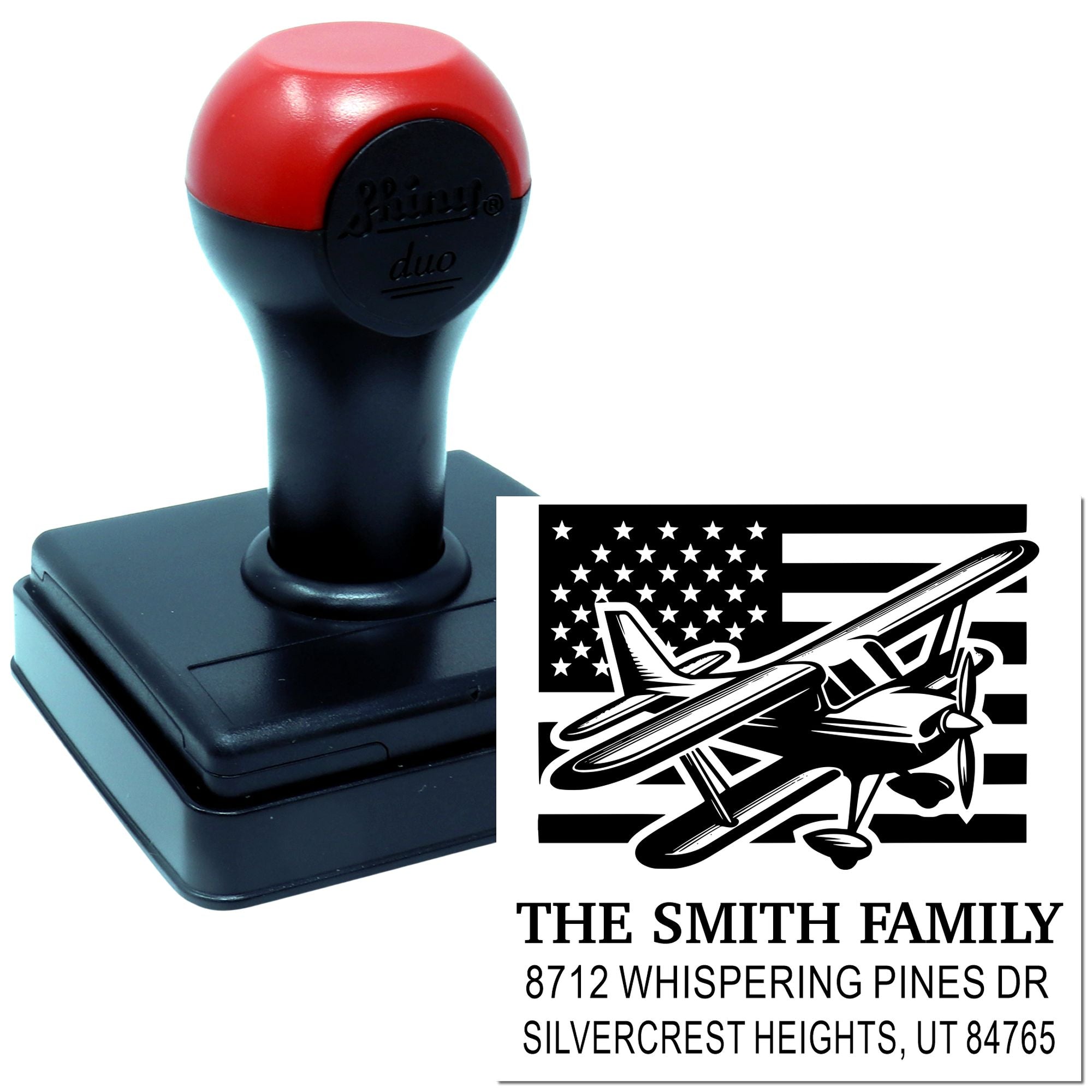 Custom self-inking address stamp with airplane and American flag design, shown beside sample imprint for The Smith Family at Whispering Pines Dr.