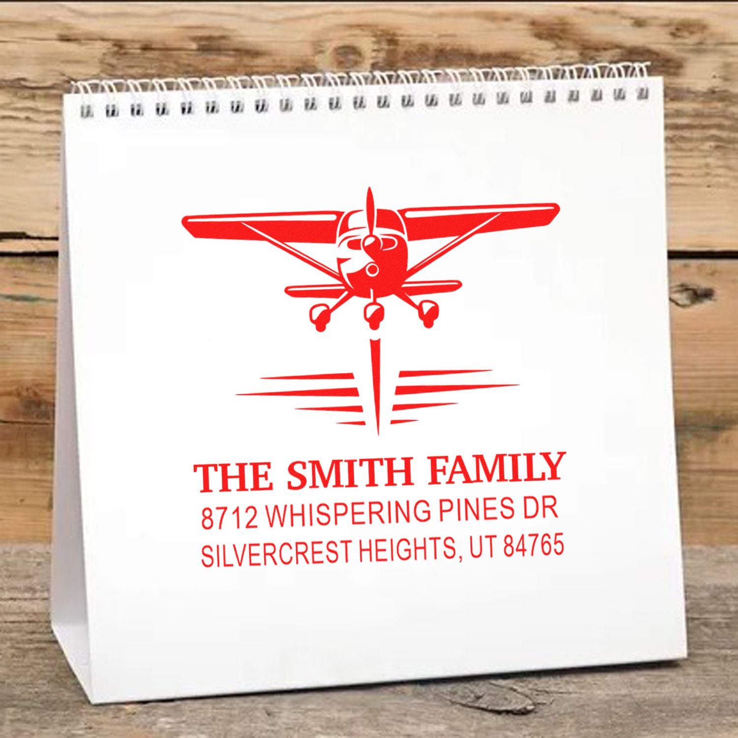 Personalized airplane return address stamp on a white gift bag, featuring The Smith Family name and Silvercrest Heights, UT address.