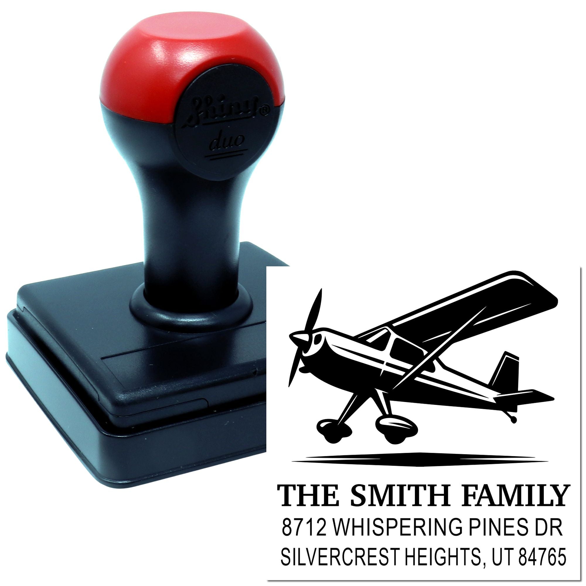 Custom self-inking address stamp with airplane design, showing the stamp and sample imprint for The Smith Family in a clean white studio setting.