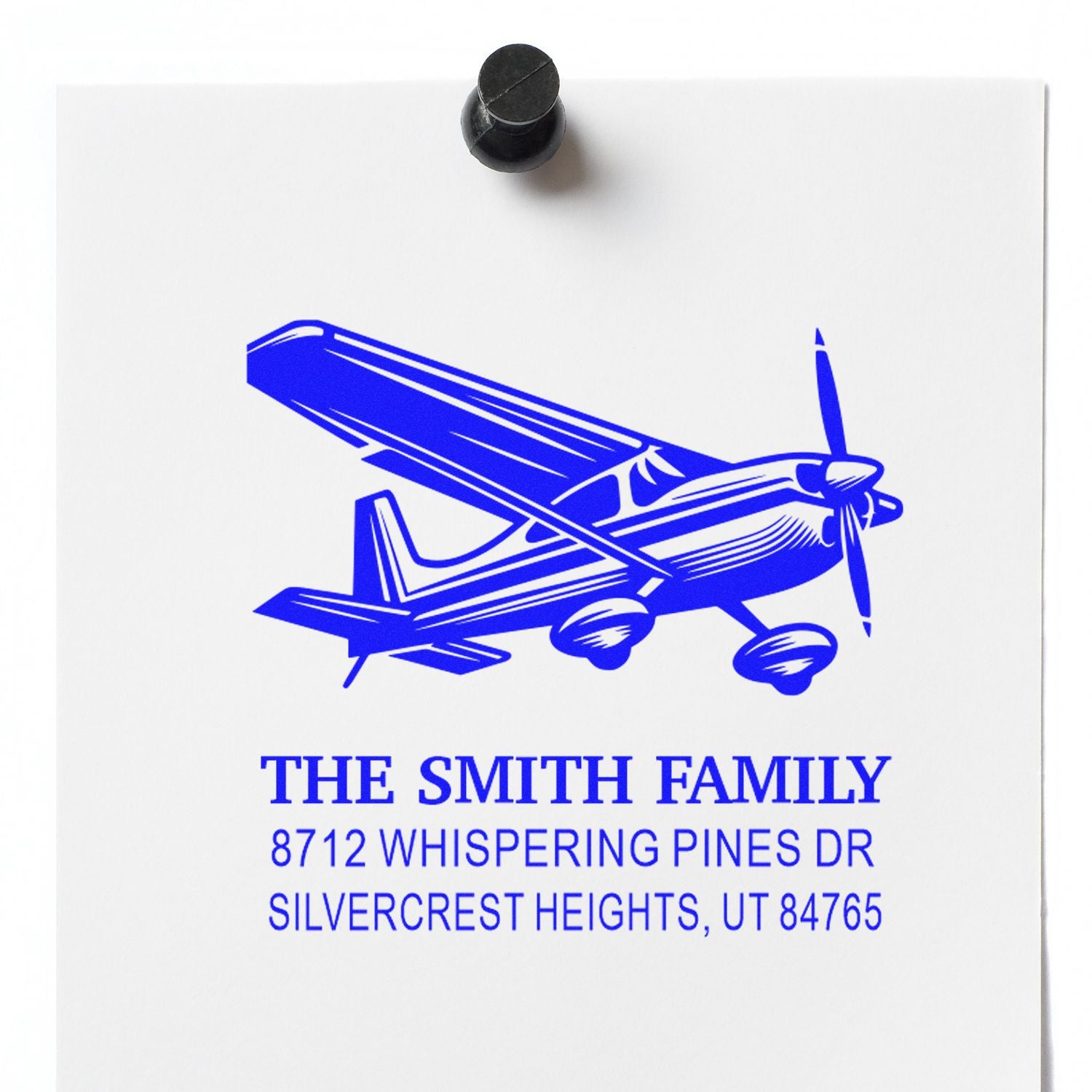 Custom blue airplane address stamp for The Smith Family, featuring a small plane and home address on white paper.