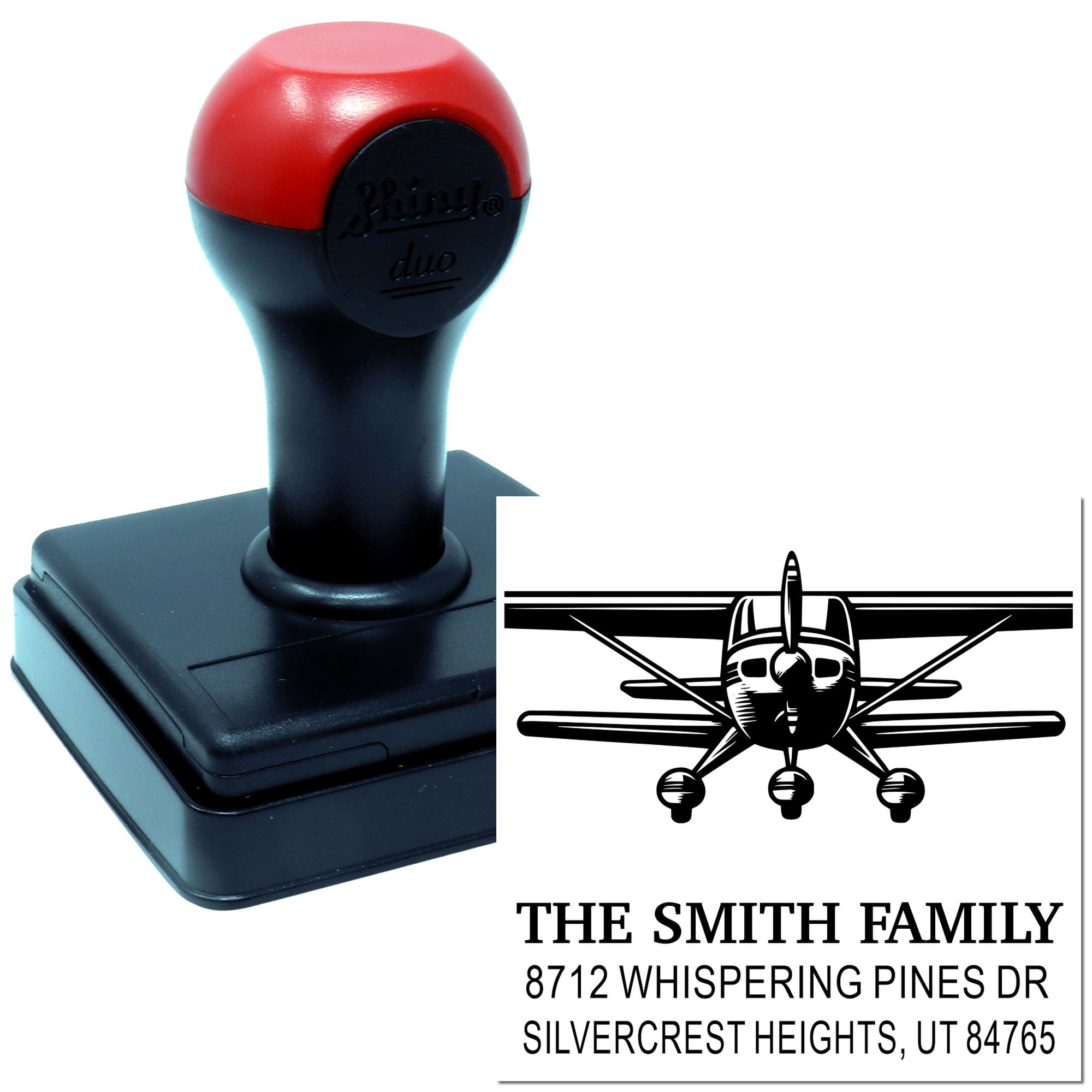Custom self-inking address stamp with airplane logo, black and red handle, and family mailing details on a white product mockup.