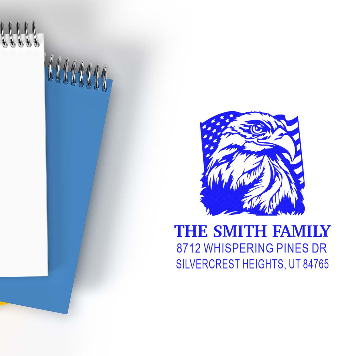 Custom blue address stamp featuring eagle design and The Smith Family address, displayed beside spiral notebooks on a white background.