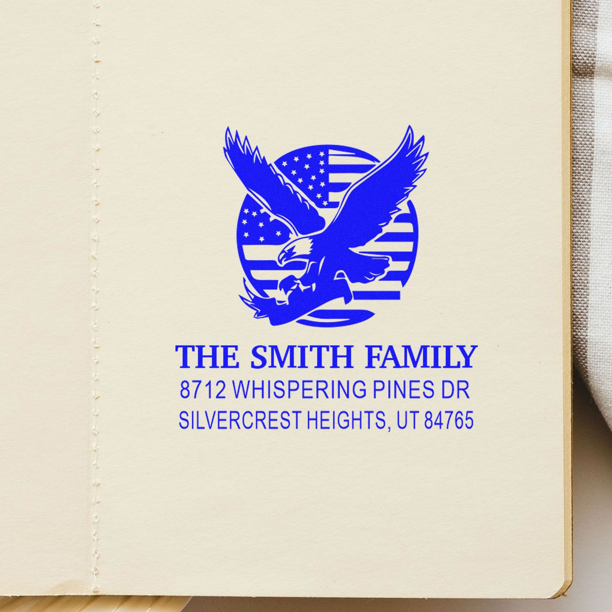 Blue personalized family address stamp with eagle and U.S. flag, reading The Smith Family, Whispering Pines Dr, Silvercrest Heights, UT on cream paper.