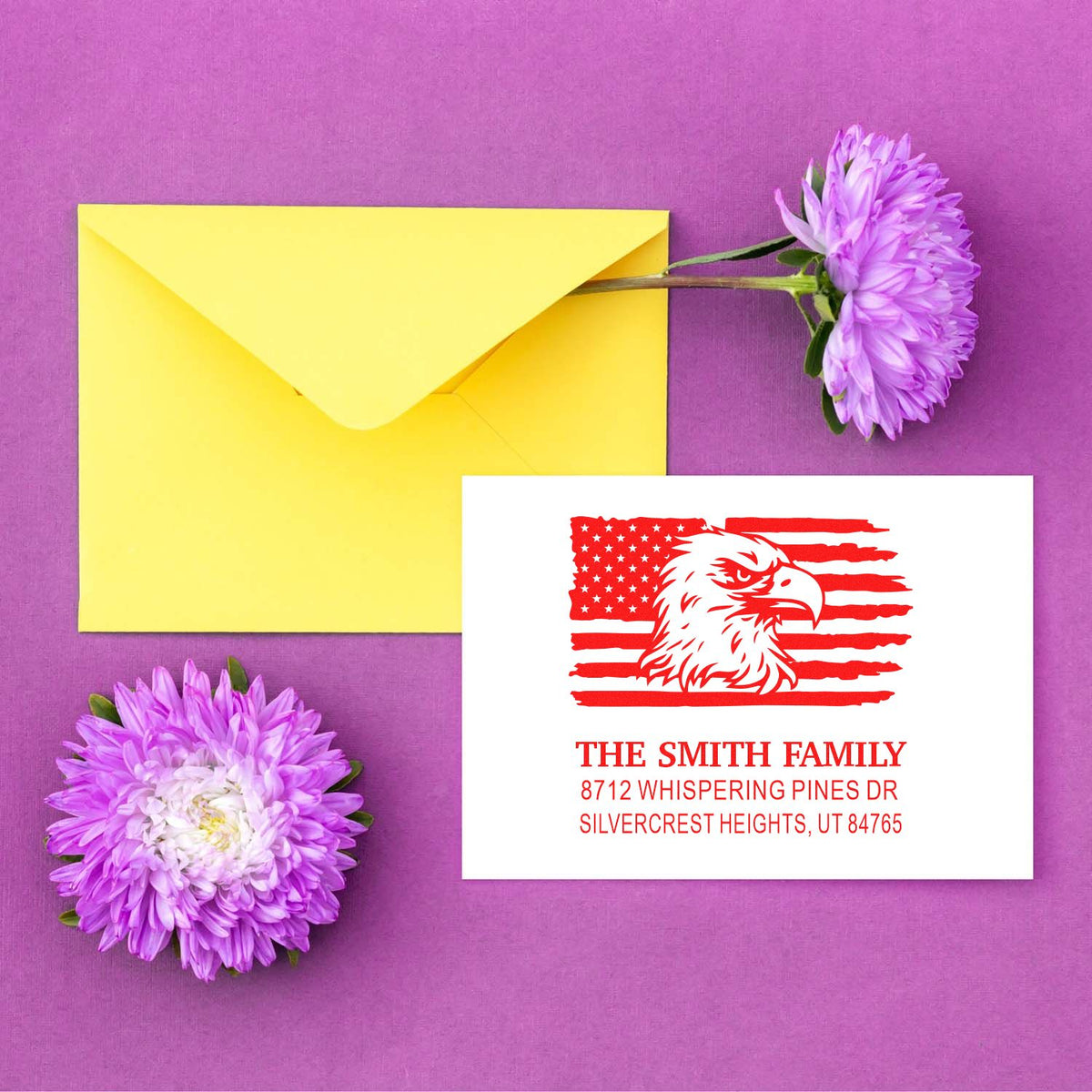 Custom address stamp with eagle and American flag, shown beside a yellow envelope and purple flowers on a purple background.