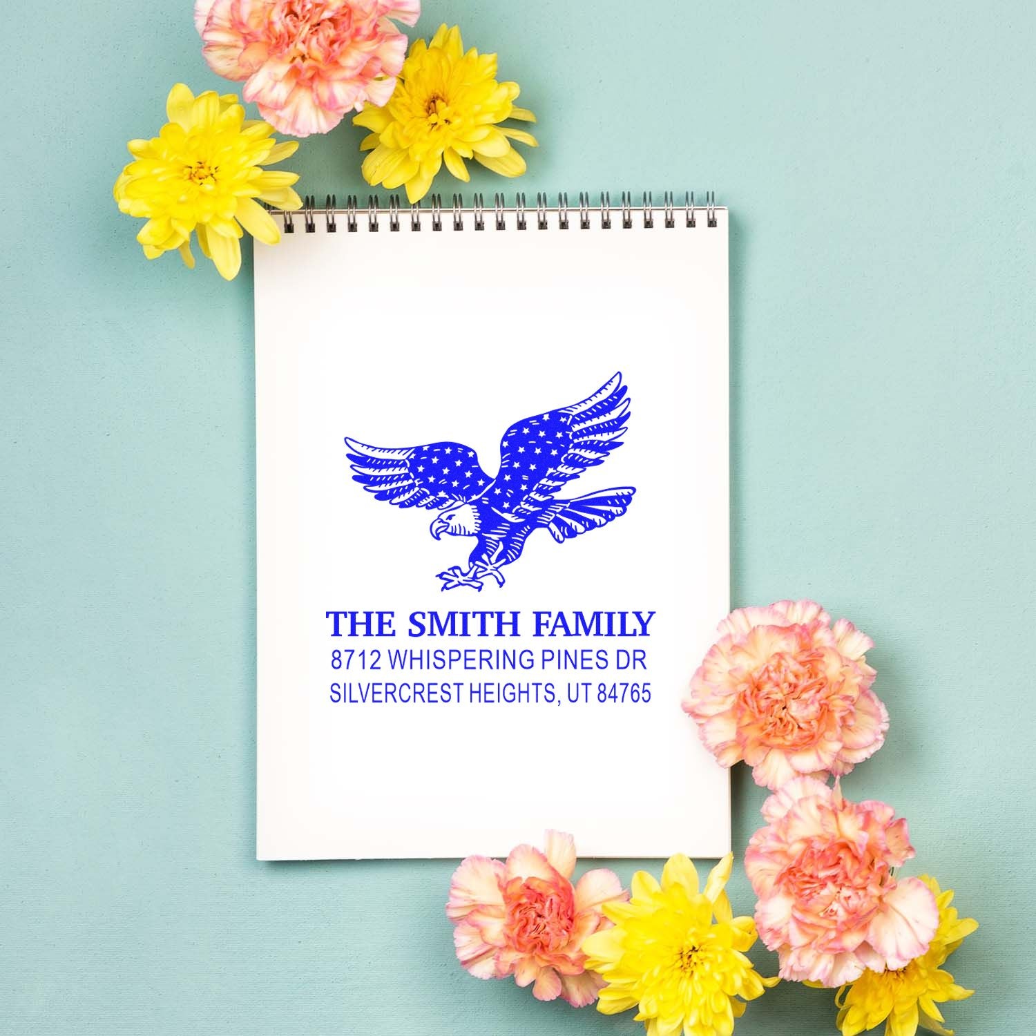Personalized blue eagle return address rubber stamp with The Smith Family name and Silvercrest Heights, UT address on a notebook with flowers.