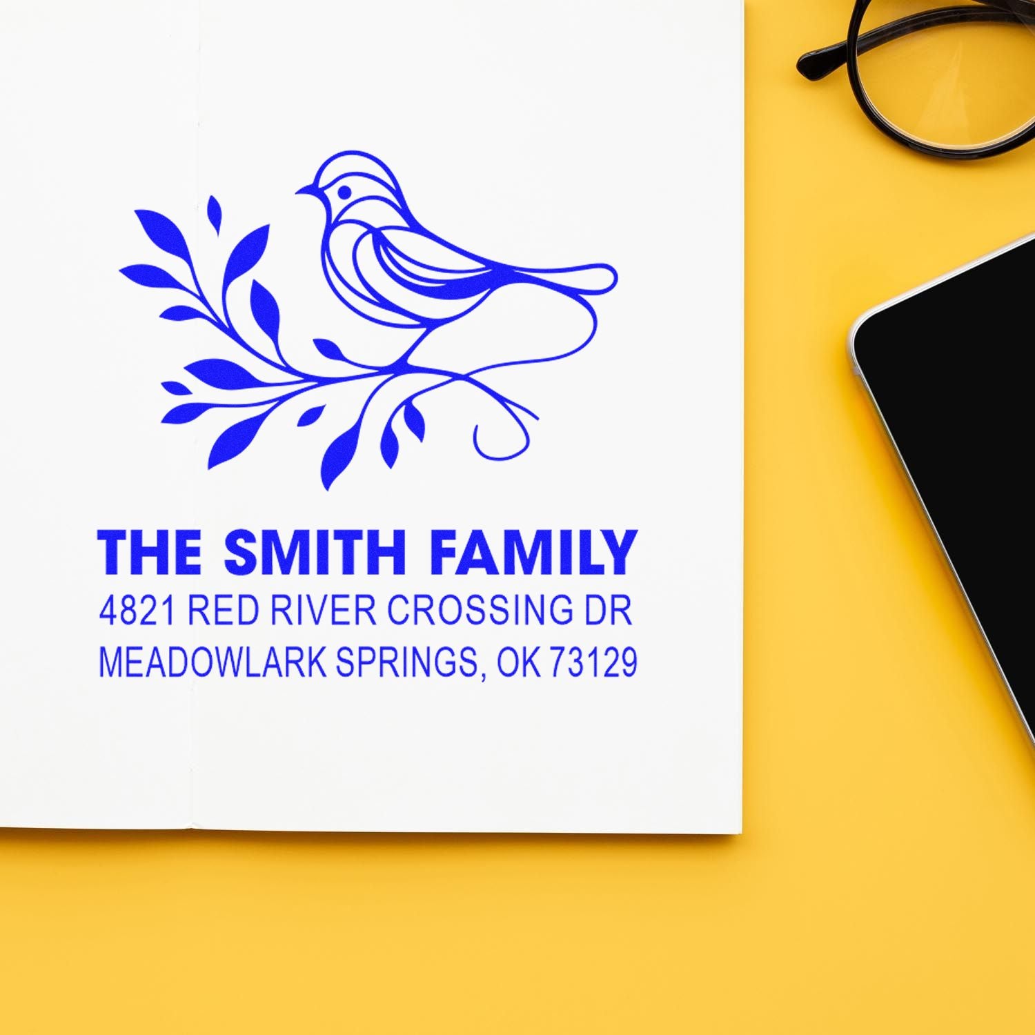 Custom rubber address stamp with bird and leaf design, The Smith Family, 4821 Red River Crossing Dr, Meadowlark Springs, OK 73129 in blue ink.