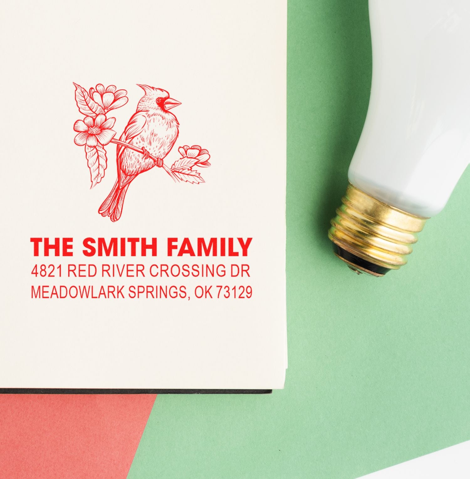 Custom rubber address stamp with bird and floral design, The Smith Family return address, red ink impression, and stamp handle on pastel background