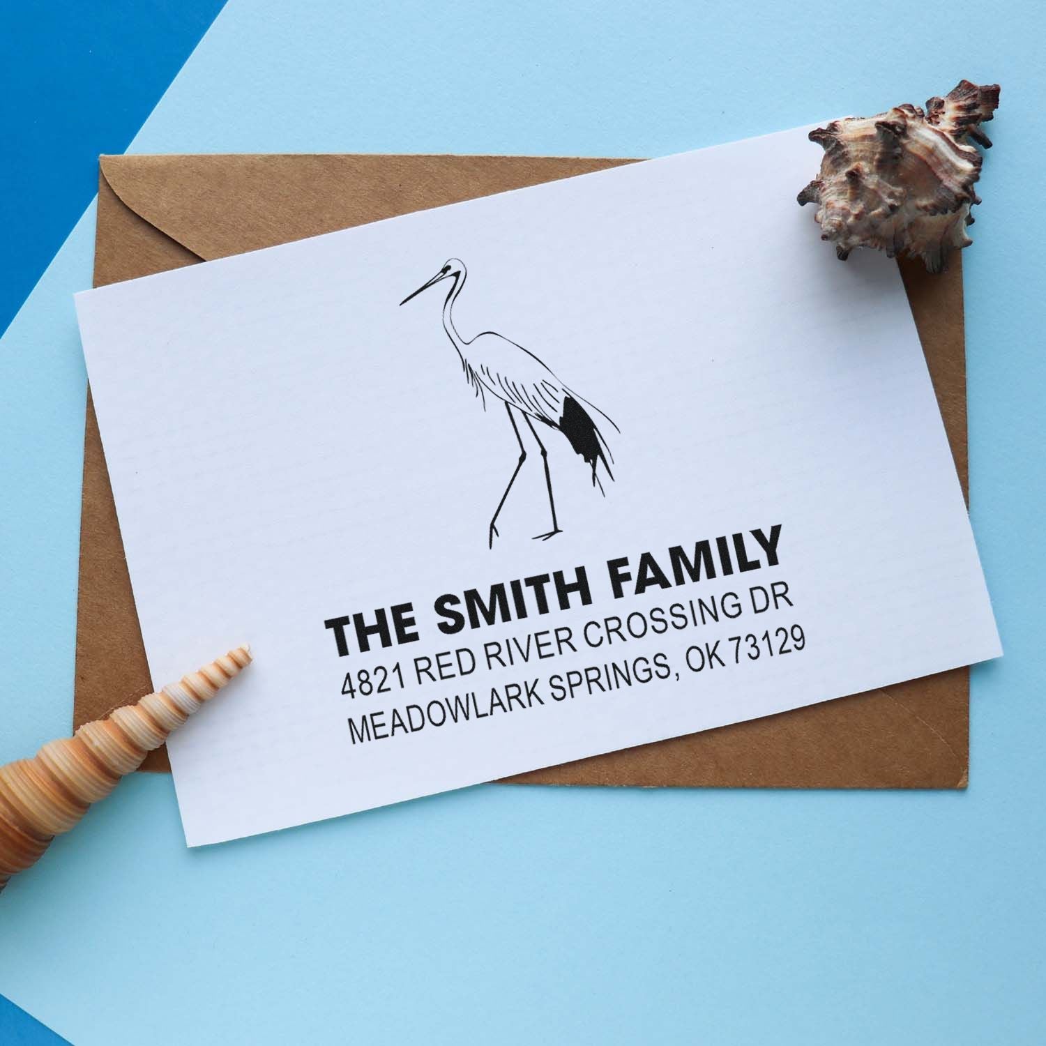Custom rubber stamp with crane illustration and return address on a white envelope, showcasing personalized family stationery for mail and invitations.