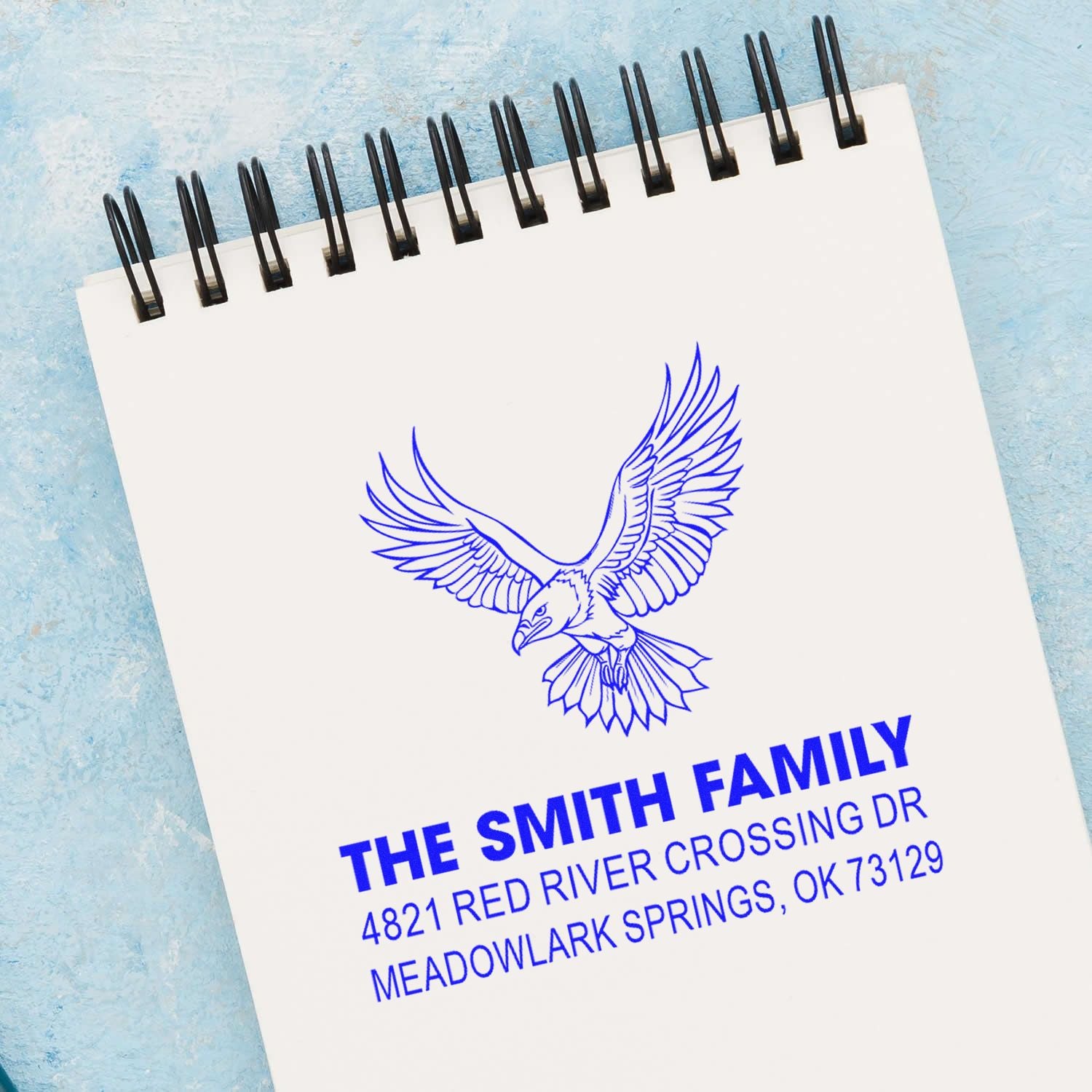 Custom address rubber stamp with flying bird logo, family name, street address and city, perfect for envelopes, stationery and business mail.