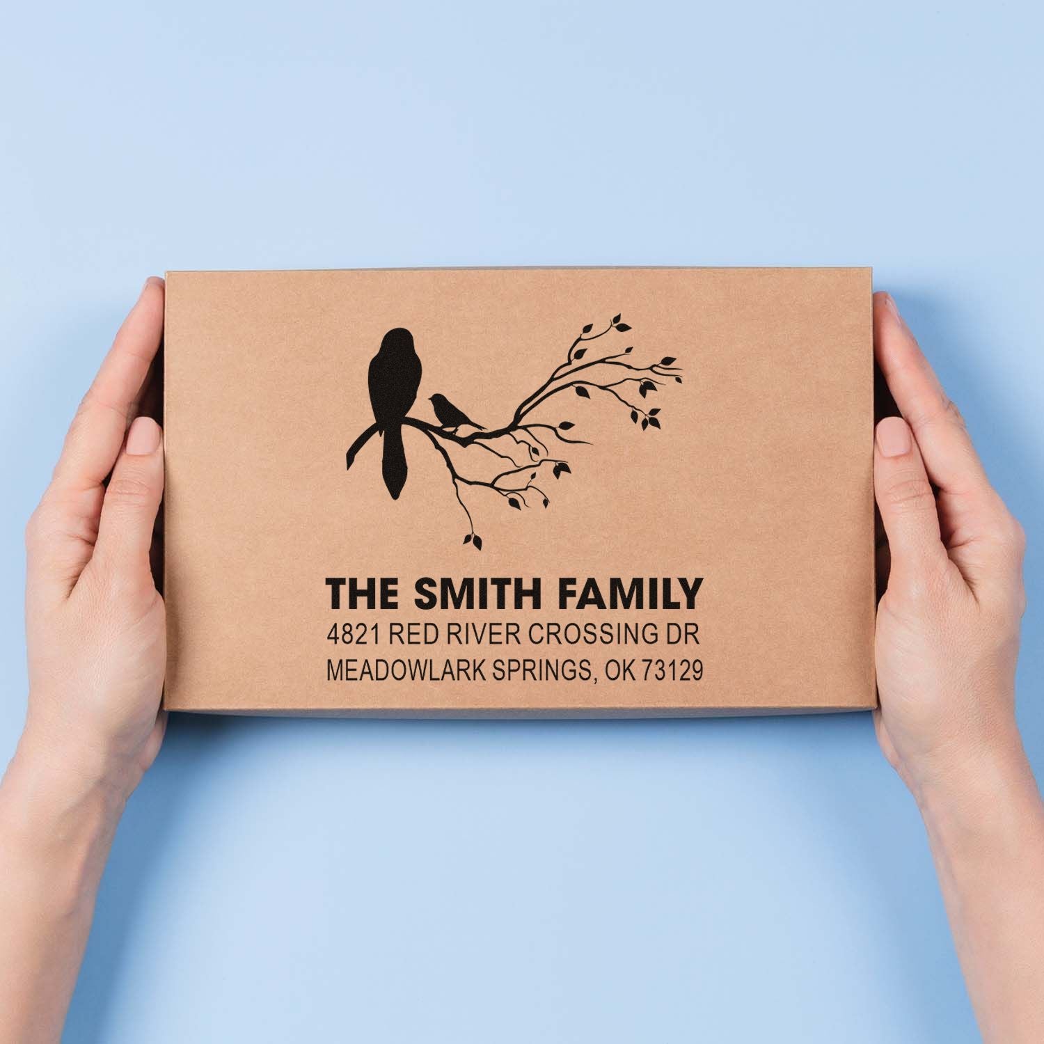 Custom rubber stamp impression on kraft box with bird and branch design, personalized with The Smith Family name and address for mailing.