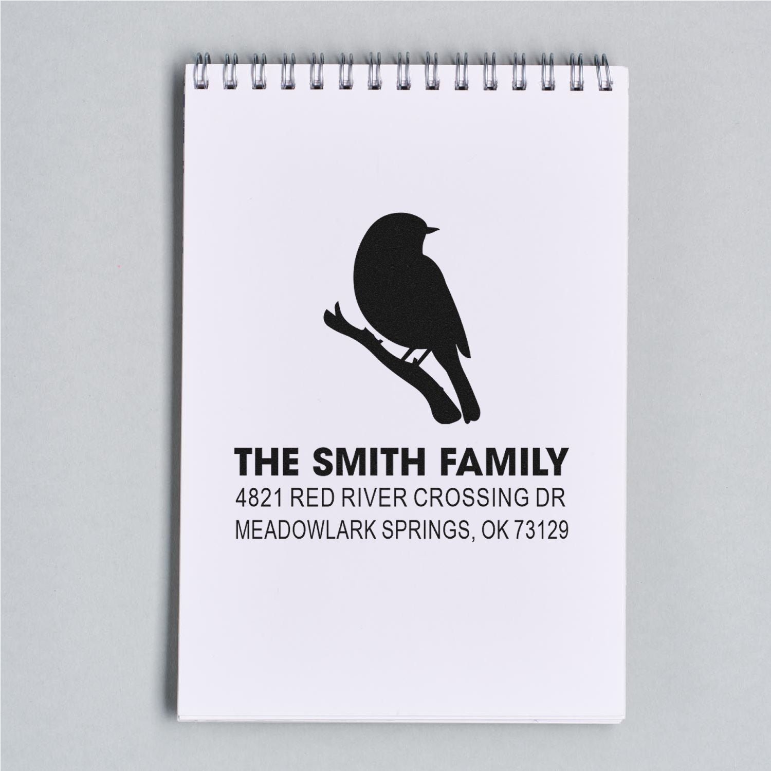 Custom family return address rubber stamp with bird silhouette logo, bold surname, and mailing address for personalized envelopes and stationery