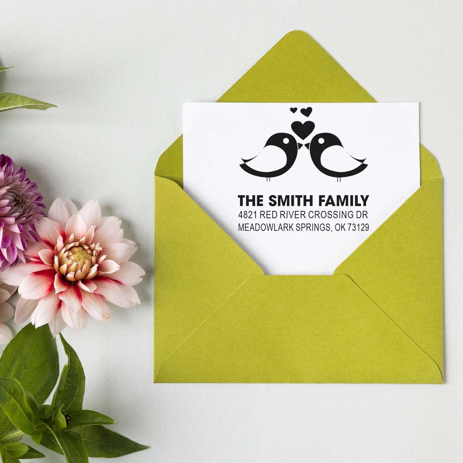 Custom rubber address stamp design with two birds and hearts for Smith family return address on white card in green envelope, personalized mailing stamp
