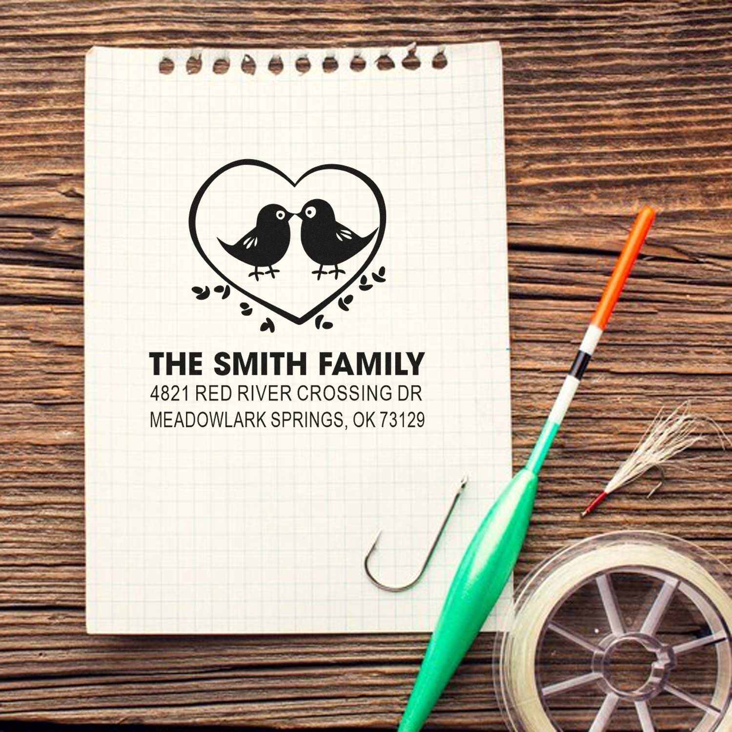 Custom rubber stamp with two birds inside a heart, personalized family name and address, ideal for wedding stationery, envelopes, and mailing crafts.