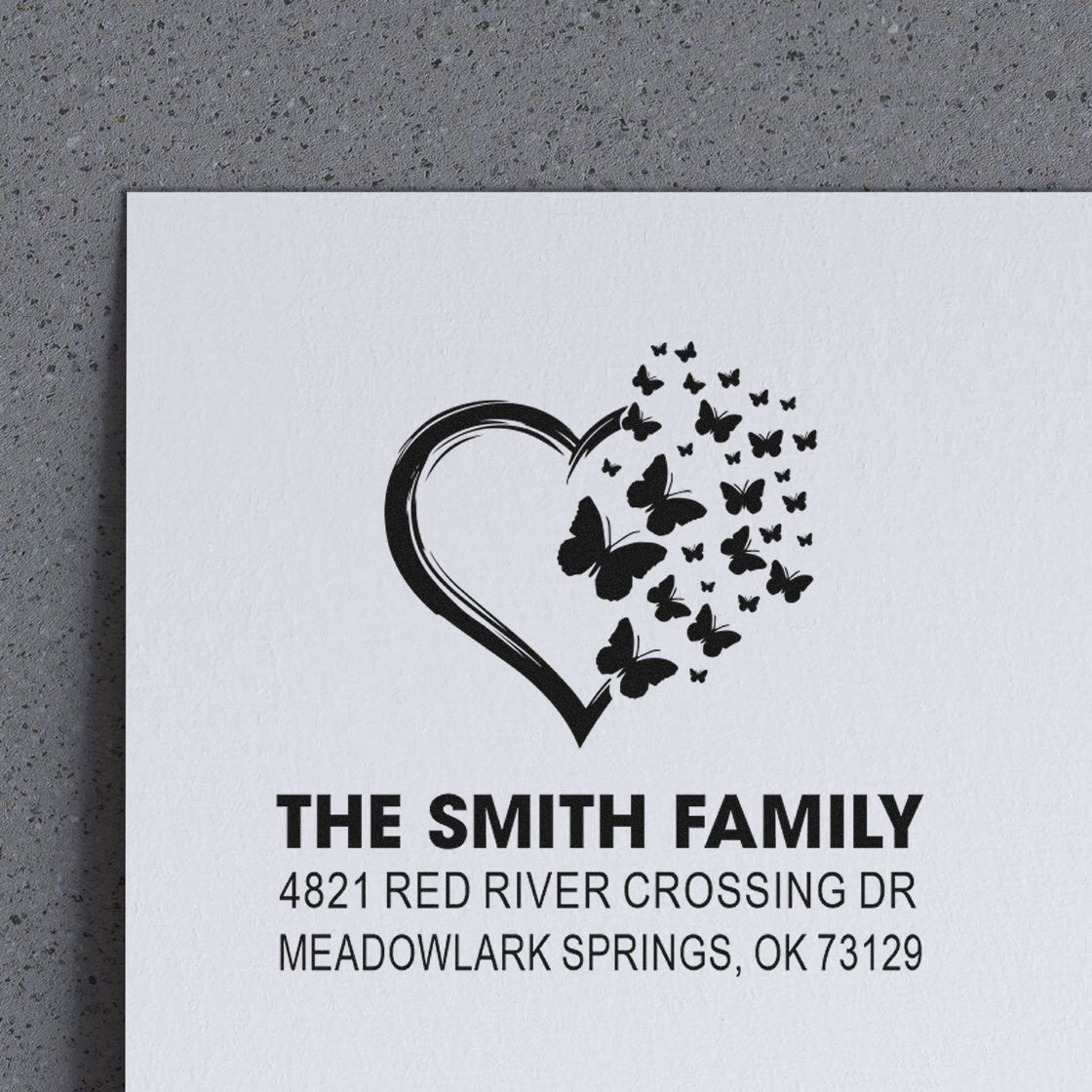 Custom family return address rubber stamp with heart and butterfly design for The Smith Family, 4821 Red River Crossing Dr, Meadowlark Springs, OK 73129.