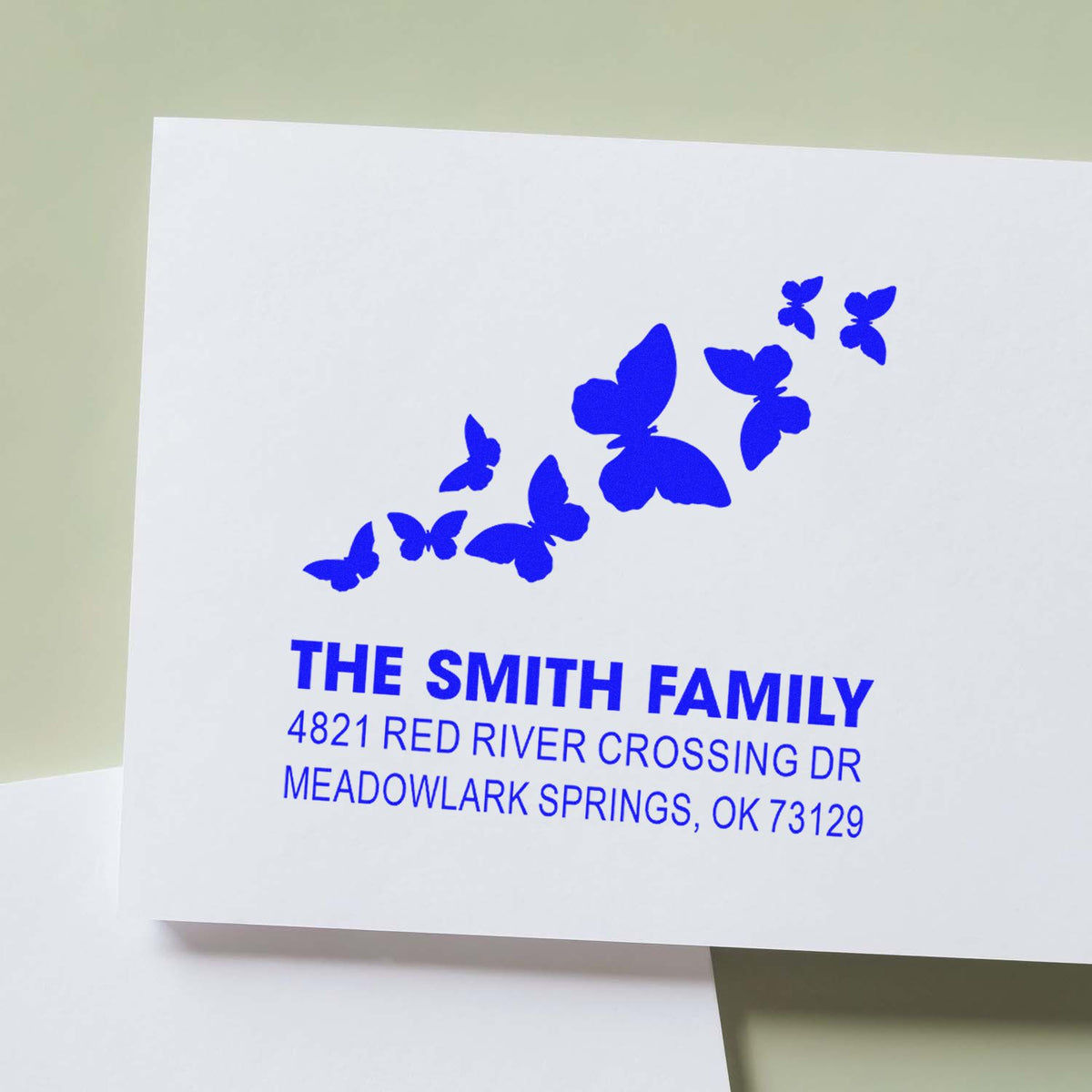 Custom butterfly return address rubber stamp for The Smith Family with blue imprint and Meadowlark Springs, OK mailing details