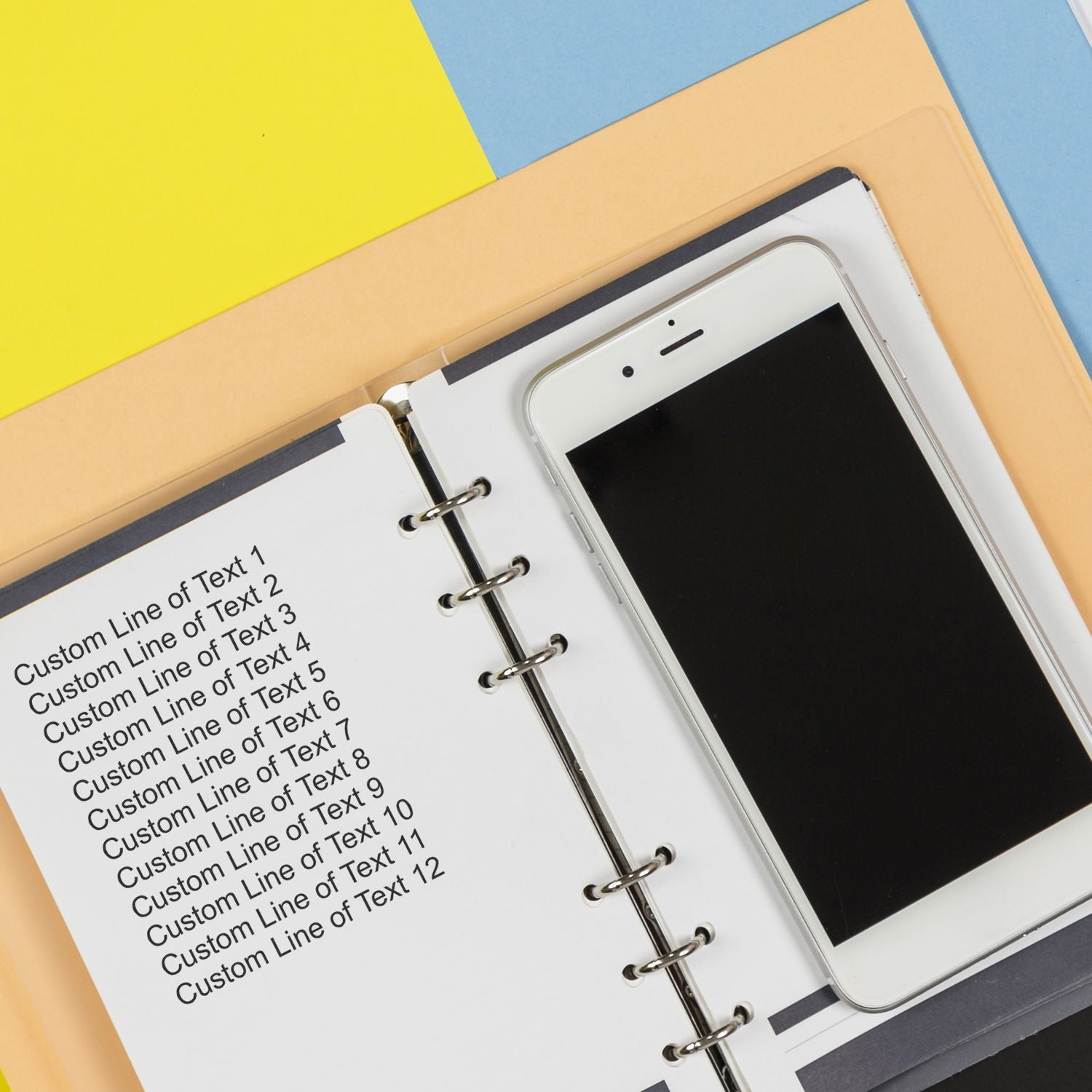 Smartphone resting on customizable planner notebook with blank lined inserts, showing layout template for organization and productivity.