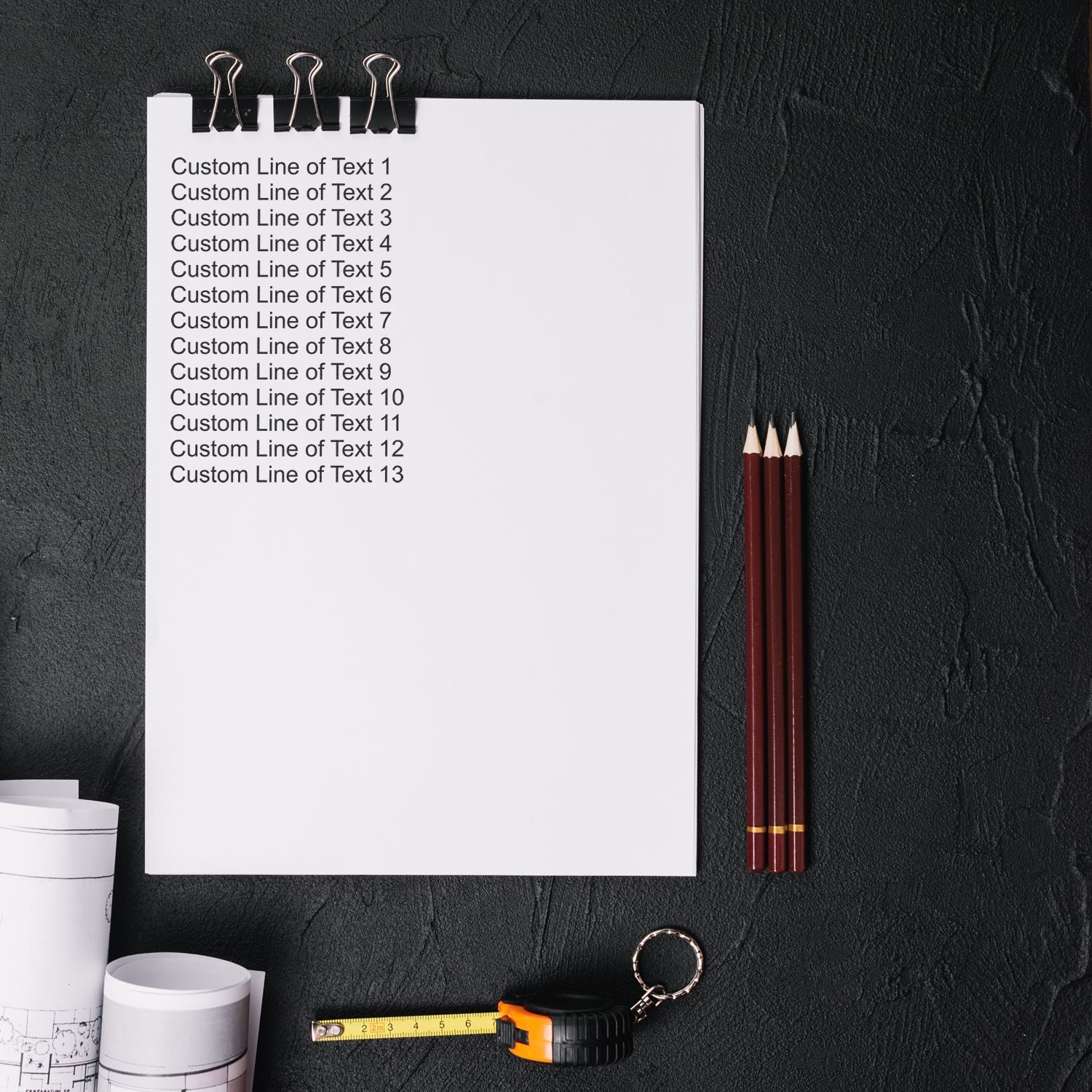 Blank notepad clipboard with custom text lines, pencils and measuring tape on dark deskstationery and office supplies mockup.