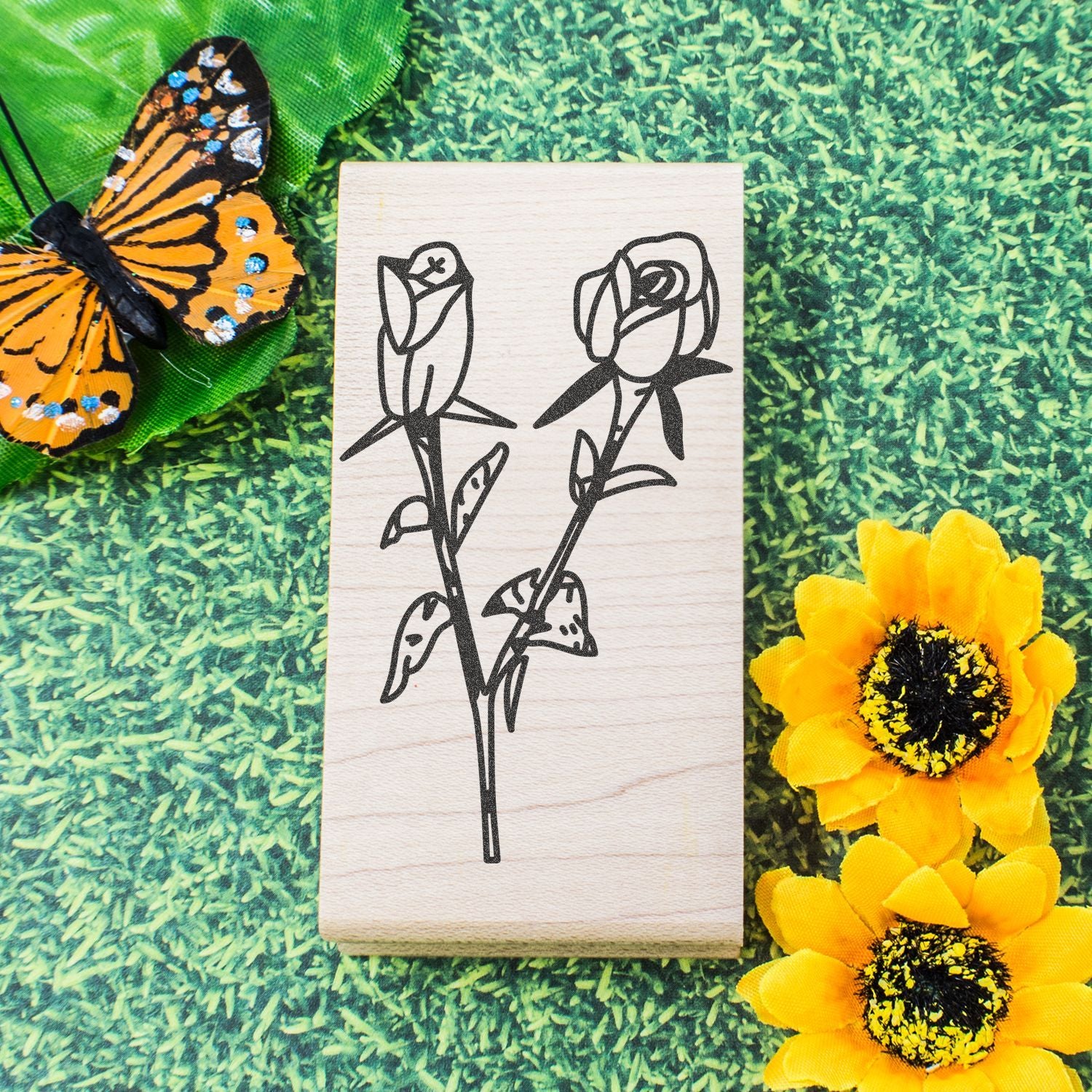 Wooden rose line art stamp with butterfly and yellow flowers on a green textured background