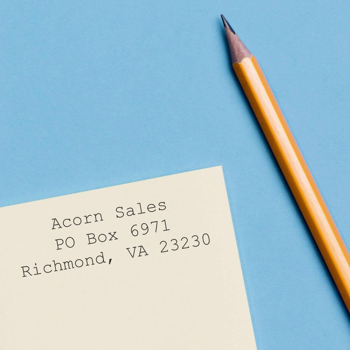 Yellow pencil and addressed envelope on blue background, stationery and mailing concept.