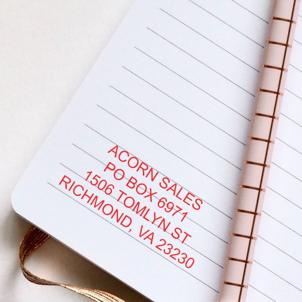 Close-up of a lined notebook with spiral binding and red address label text, office stationery background.