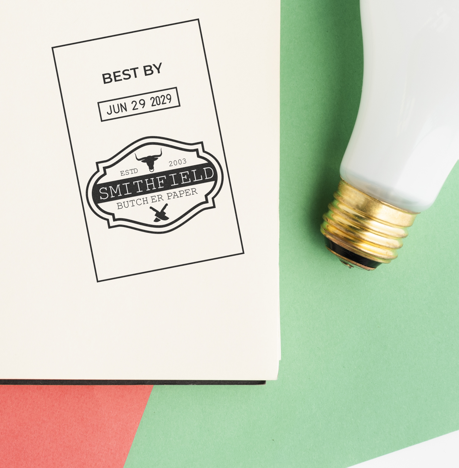 Custom butcher paper packaging label with Best By Jun 29 2029 stamp beside a vintage light bulb on a green background
