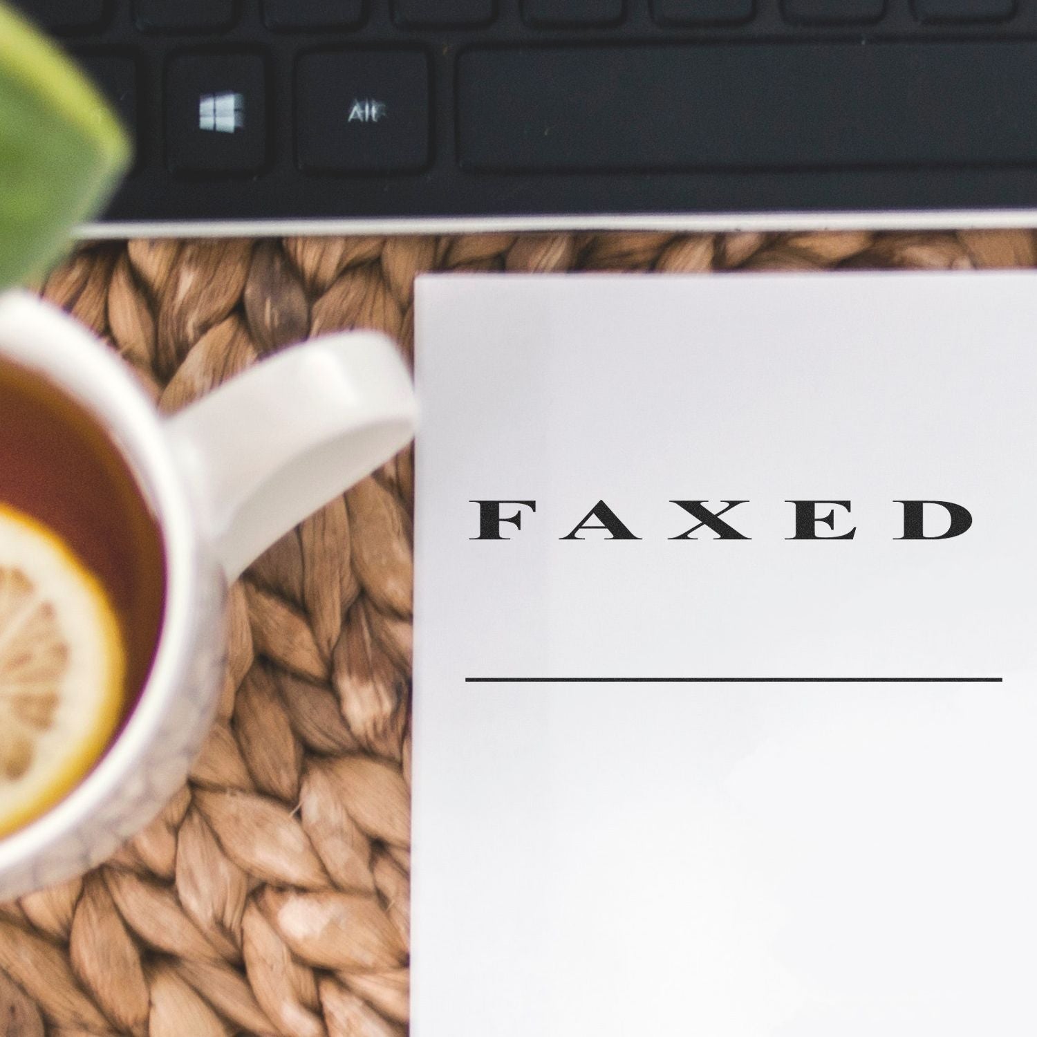 Close-up of the word FAXED on a document cover, with office keyboard background suggesting faxed paperwork services.