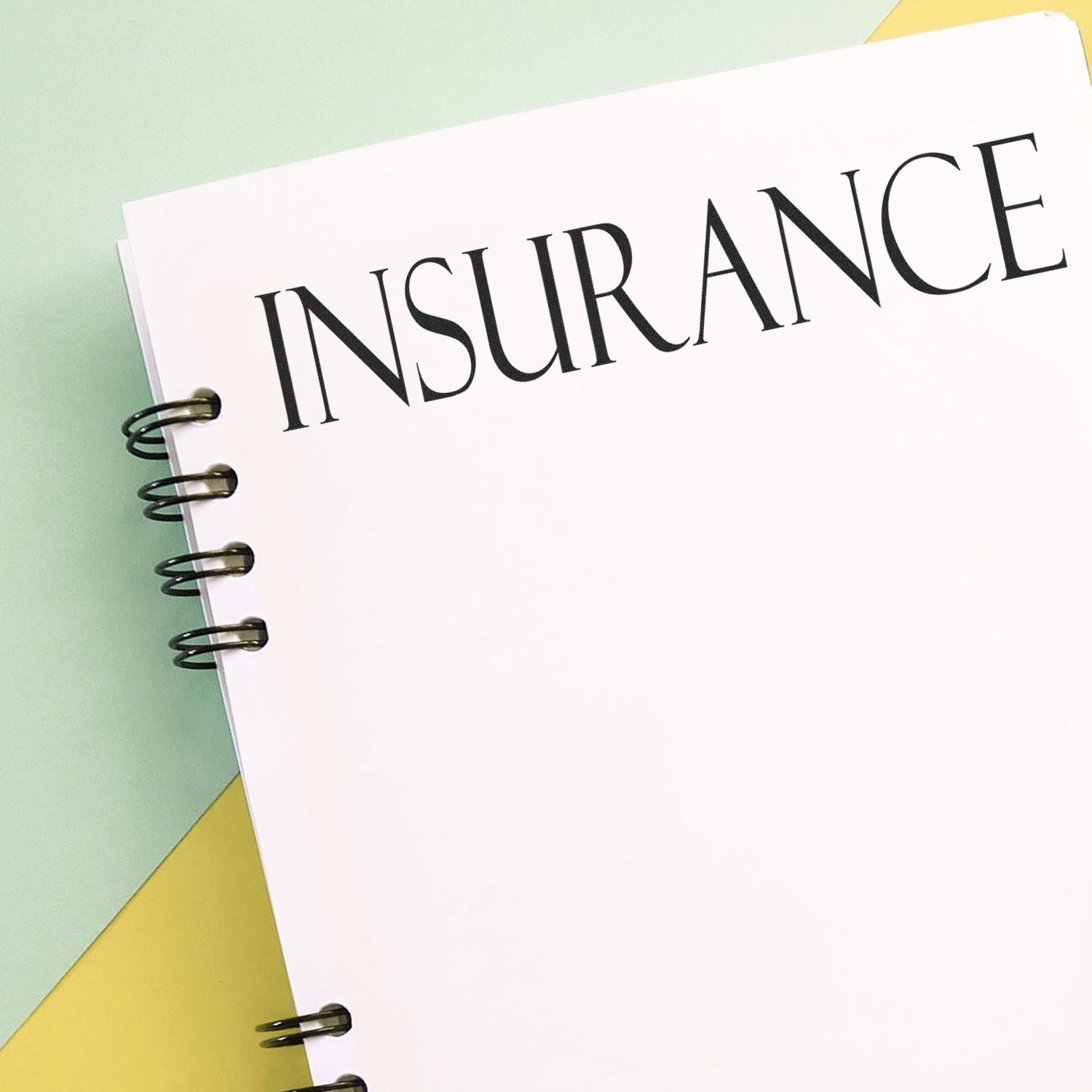 Insurance concept image: spiral notebook labeled INSURANCE, symbolizing coverage, risk protection, and planning.