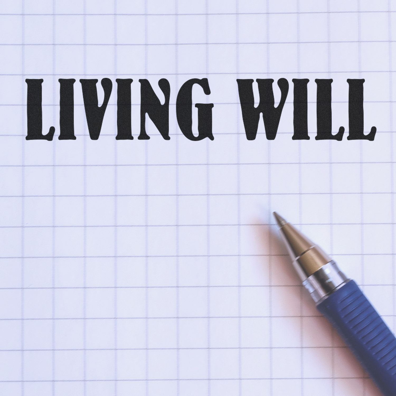 Living will document concept: LIVING WILL handwritten in bold on lined paper with a pen, end-of-life planning