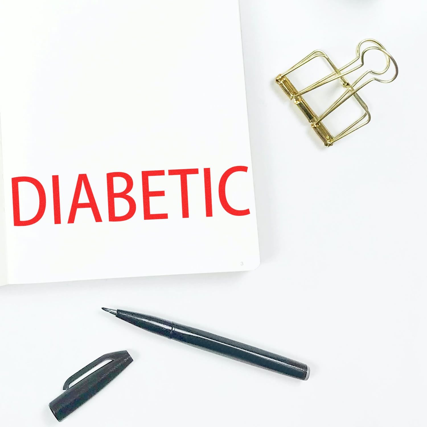 Diabetic notebook with red DIABETIC title, paperclip and pendiabetes awareness and care planning.