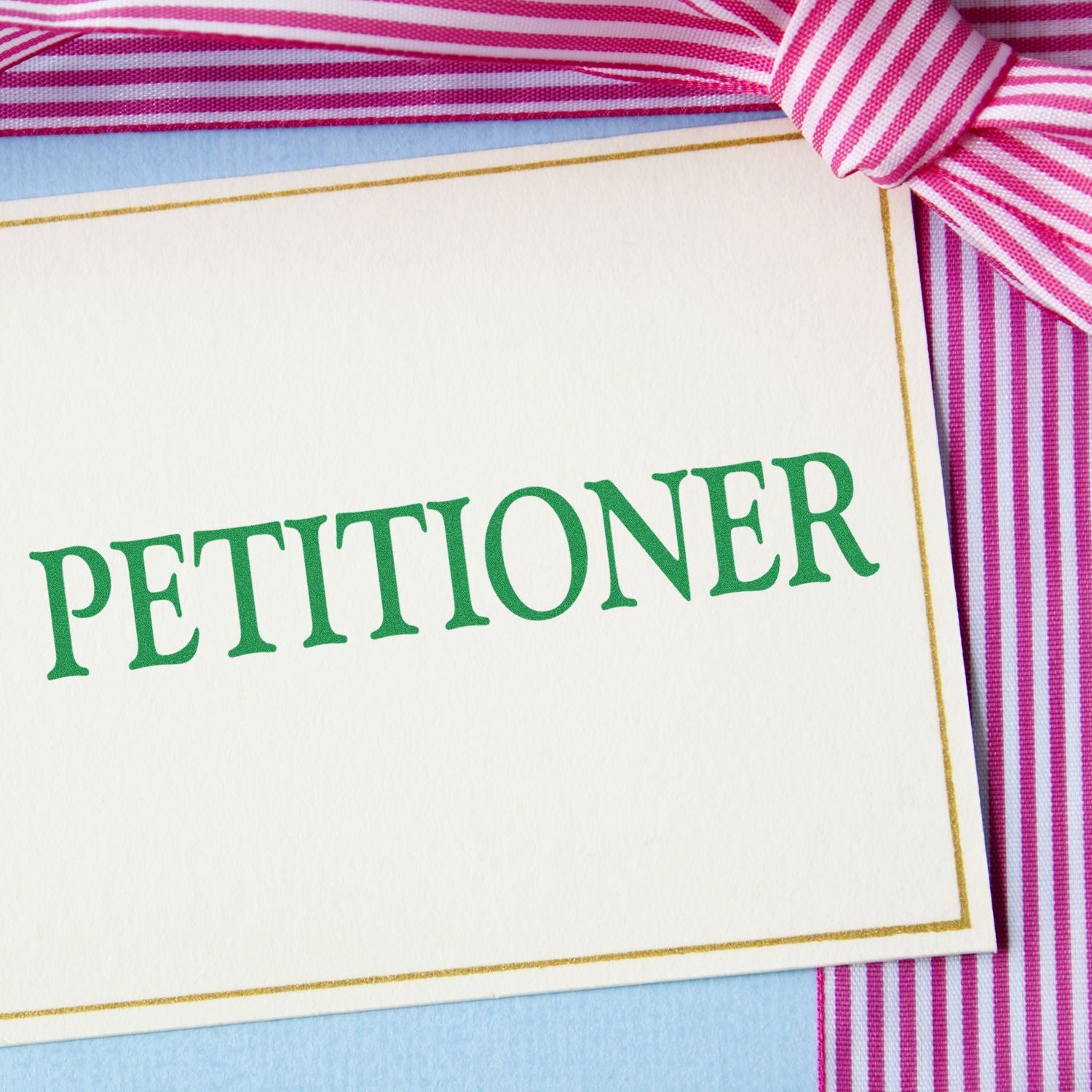 Close-up of a legal document labeled PETITIONER on white paper with pink striped fabric background.