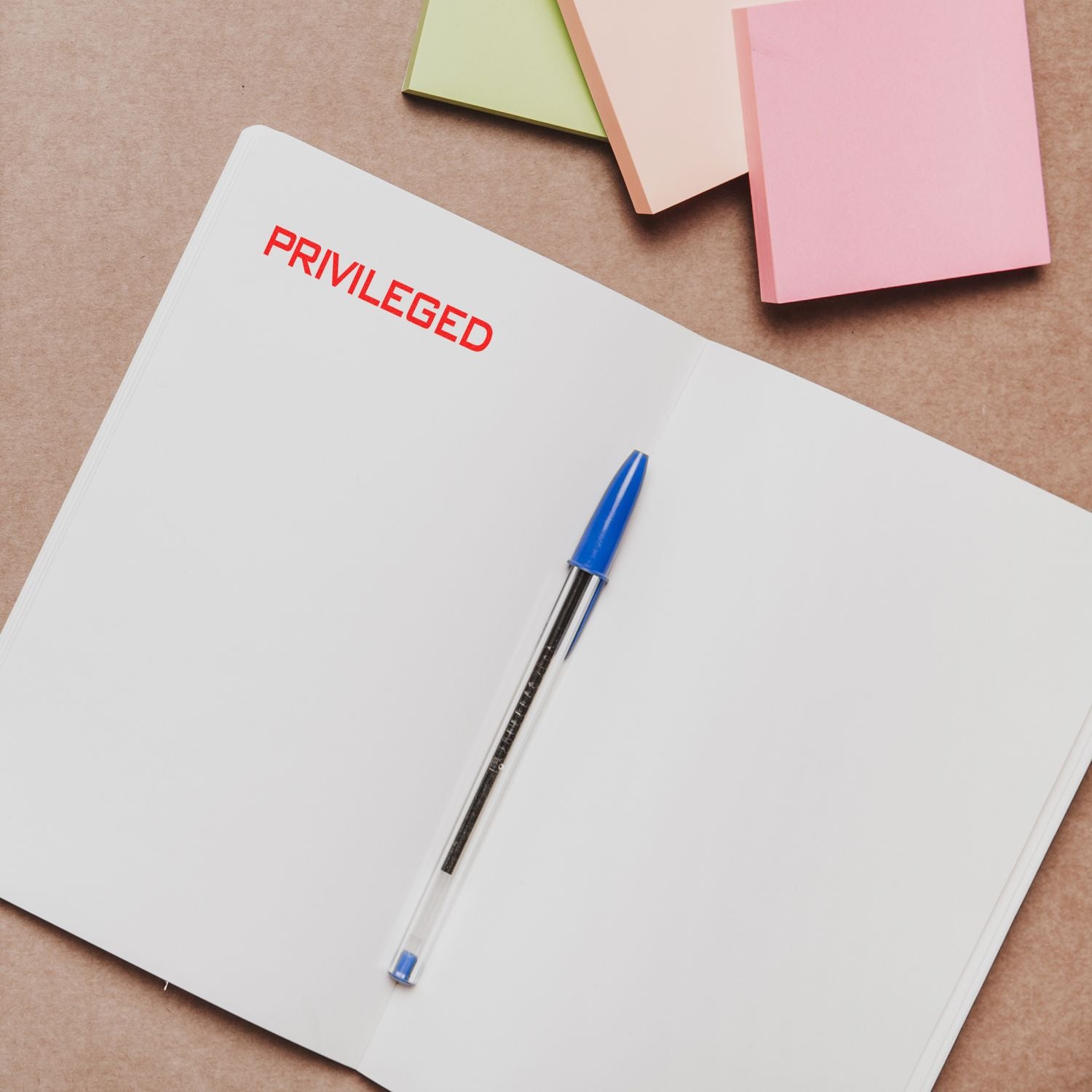 Privileged notebook with pen and colored papers, promoting stationery brand and document design.