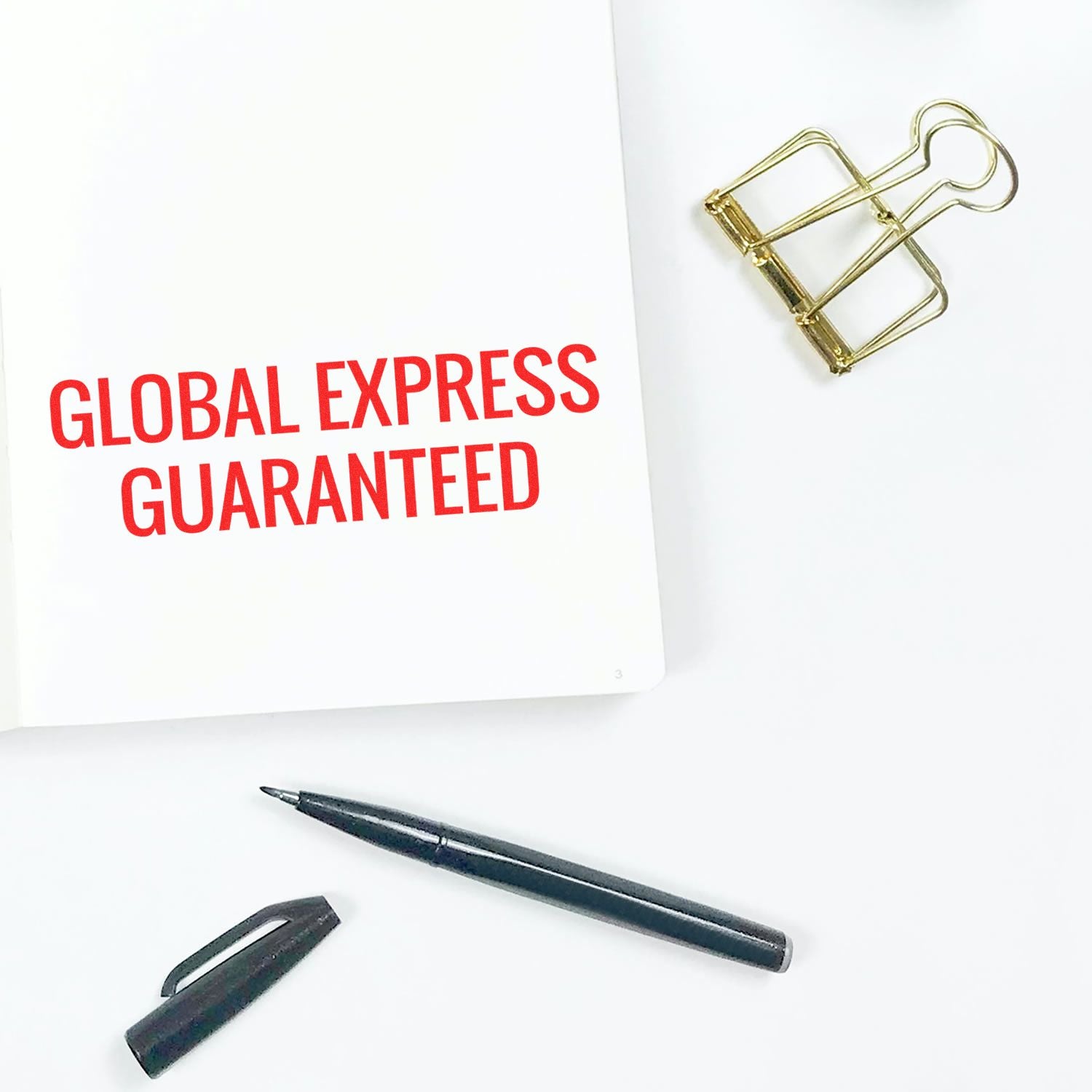 Global Express Guaranteed shipping promotional card with gold paperclip and pen on white background