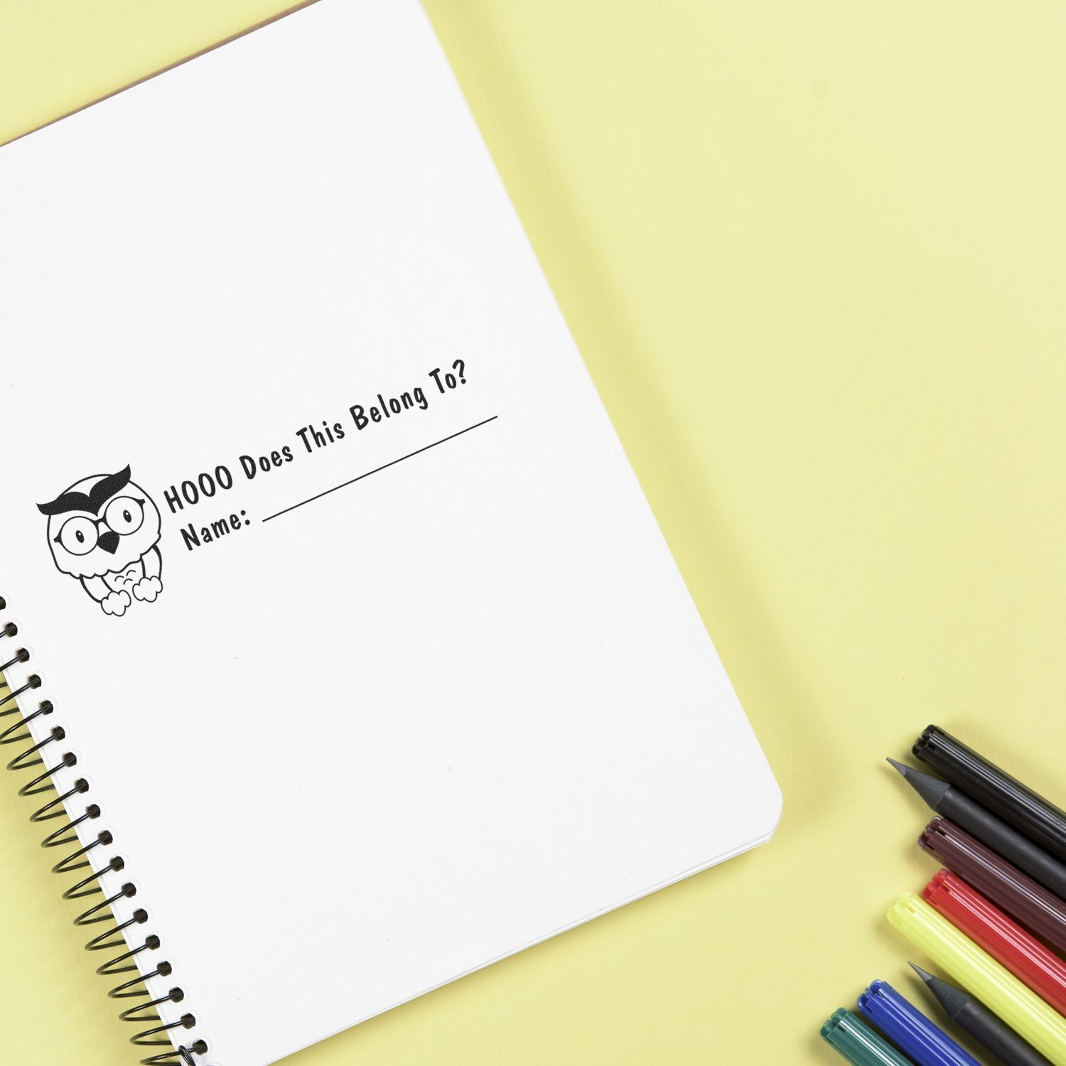 Cute owl stationery name tag on notebook page: Hooo Does This Belong To! with Name line, classroom supplies on yellow background.